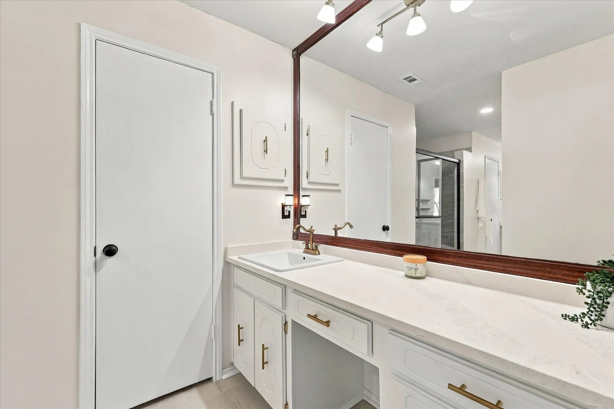 White vanity with gold-tone hardware, integrated sink, and extended countertop