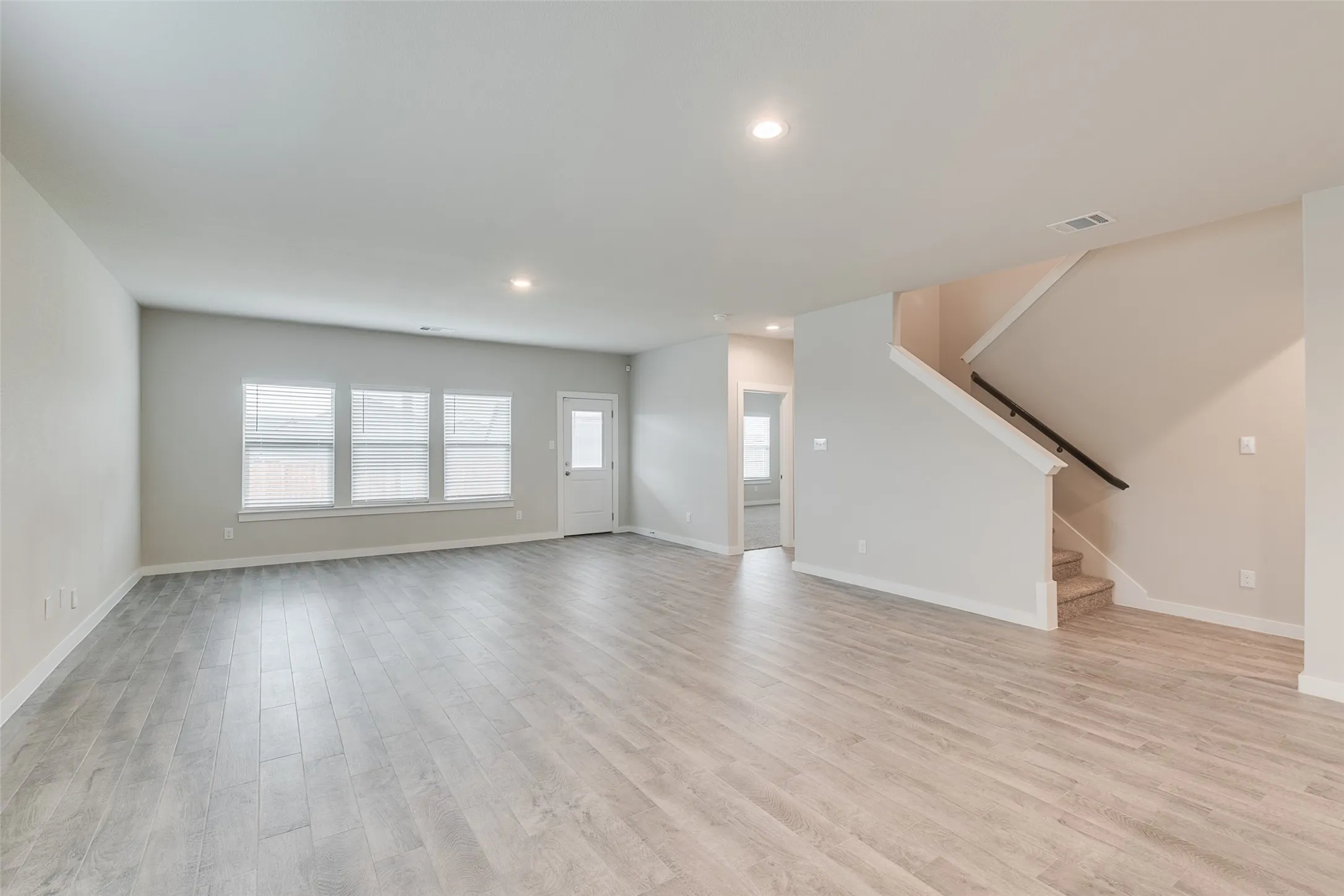 Spacious living area featuring wood-finish flooring, recessed lighting, and multiple windows