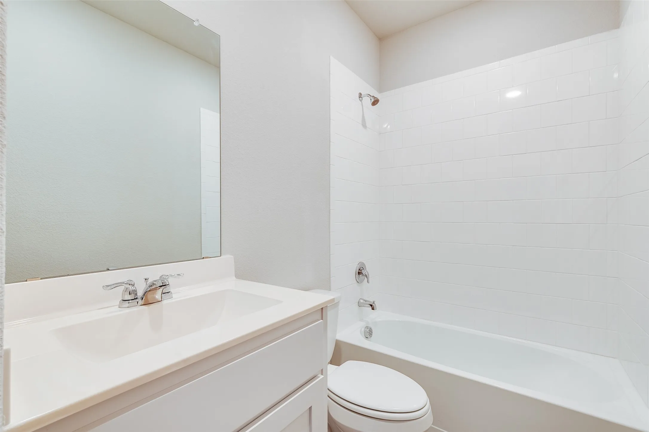 Bathroom featuring a white vanity with an integrated sink, polished chrome faucet, and a large mirror
