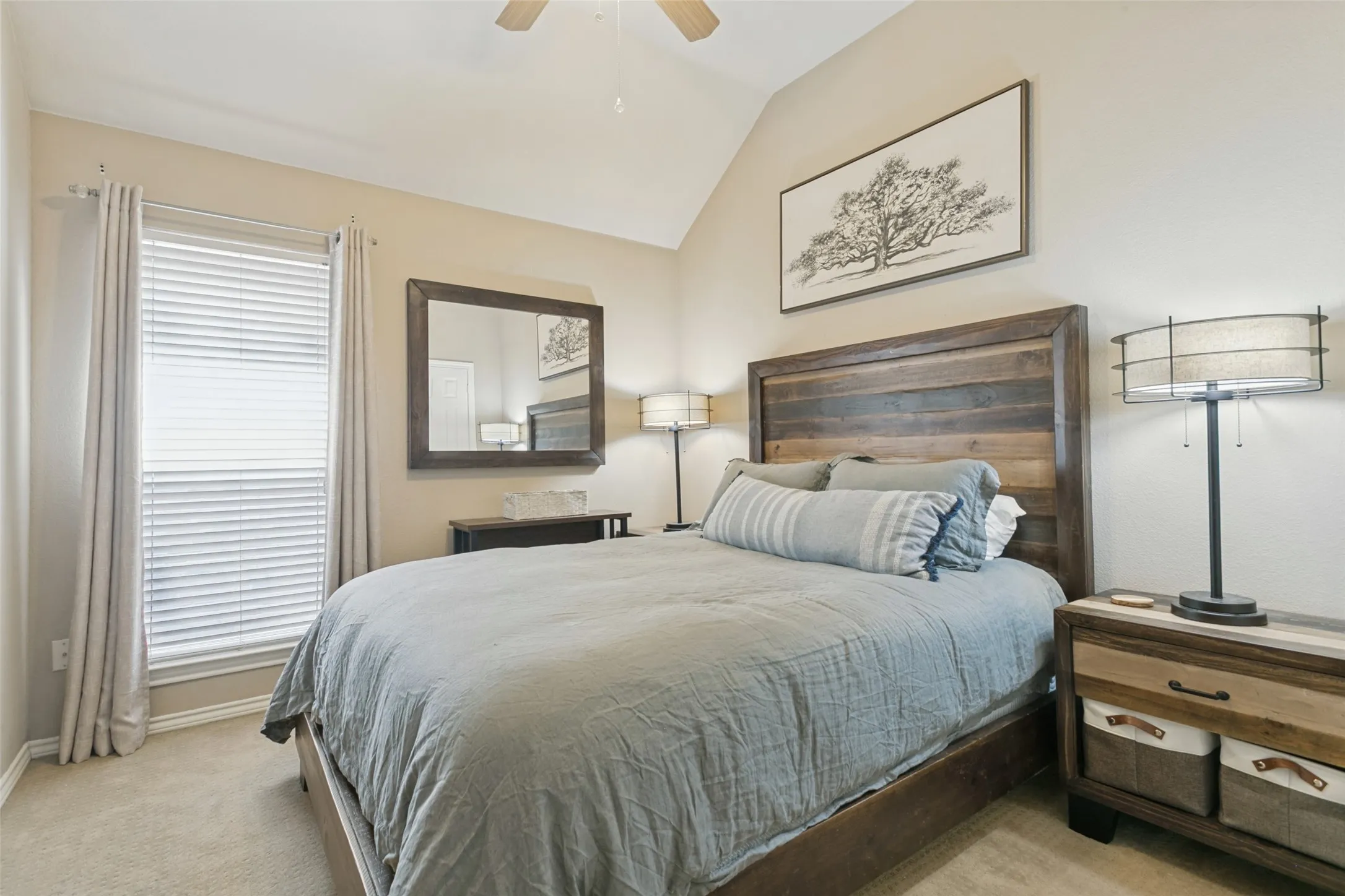 Vaulted ceiling with a ceiling fan, window with blinds, wood-finish headboard, and neutral carpeting