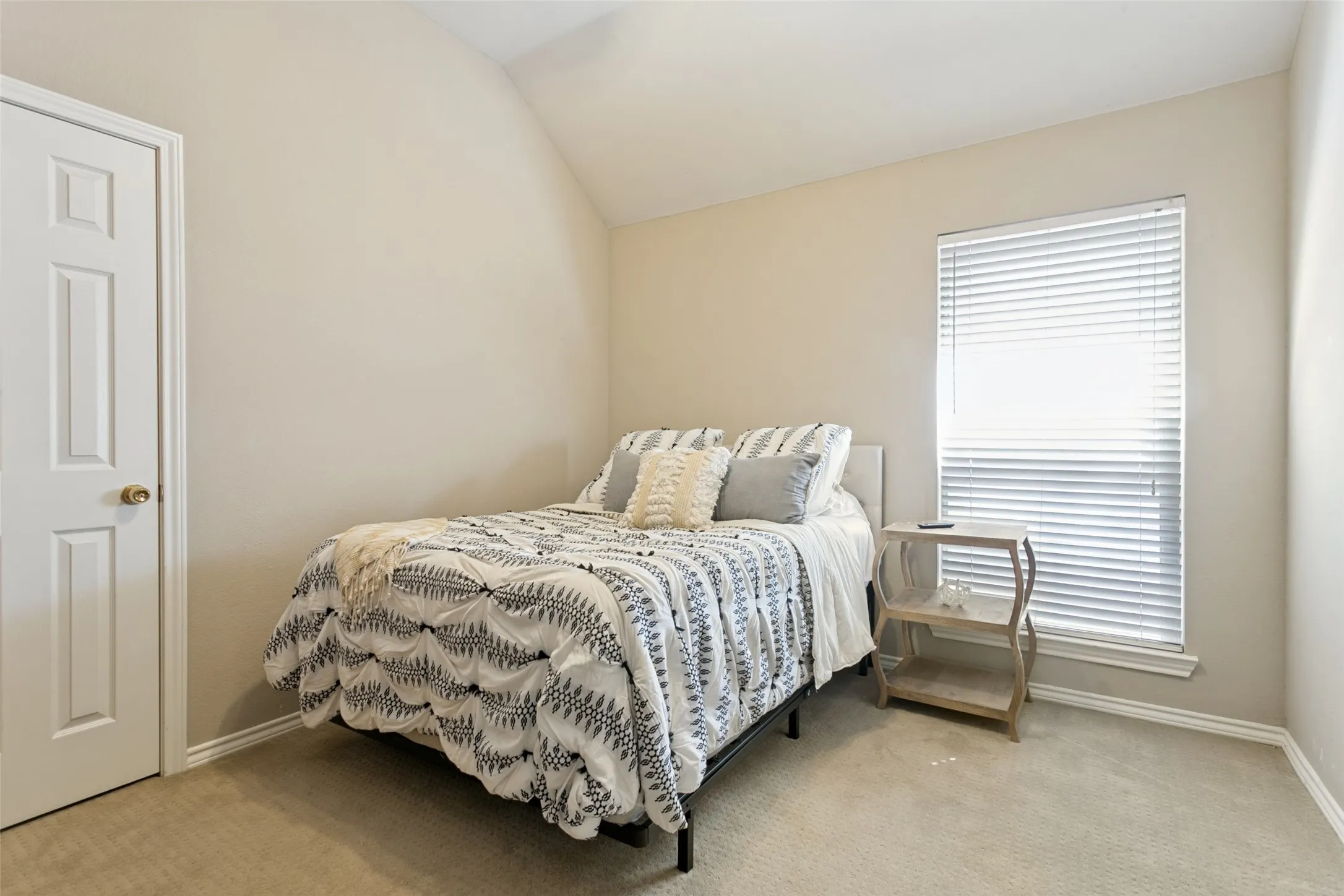 Neutral tone wall finishes, vaulted ceiling, and carpeted flooring