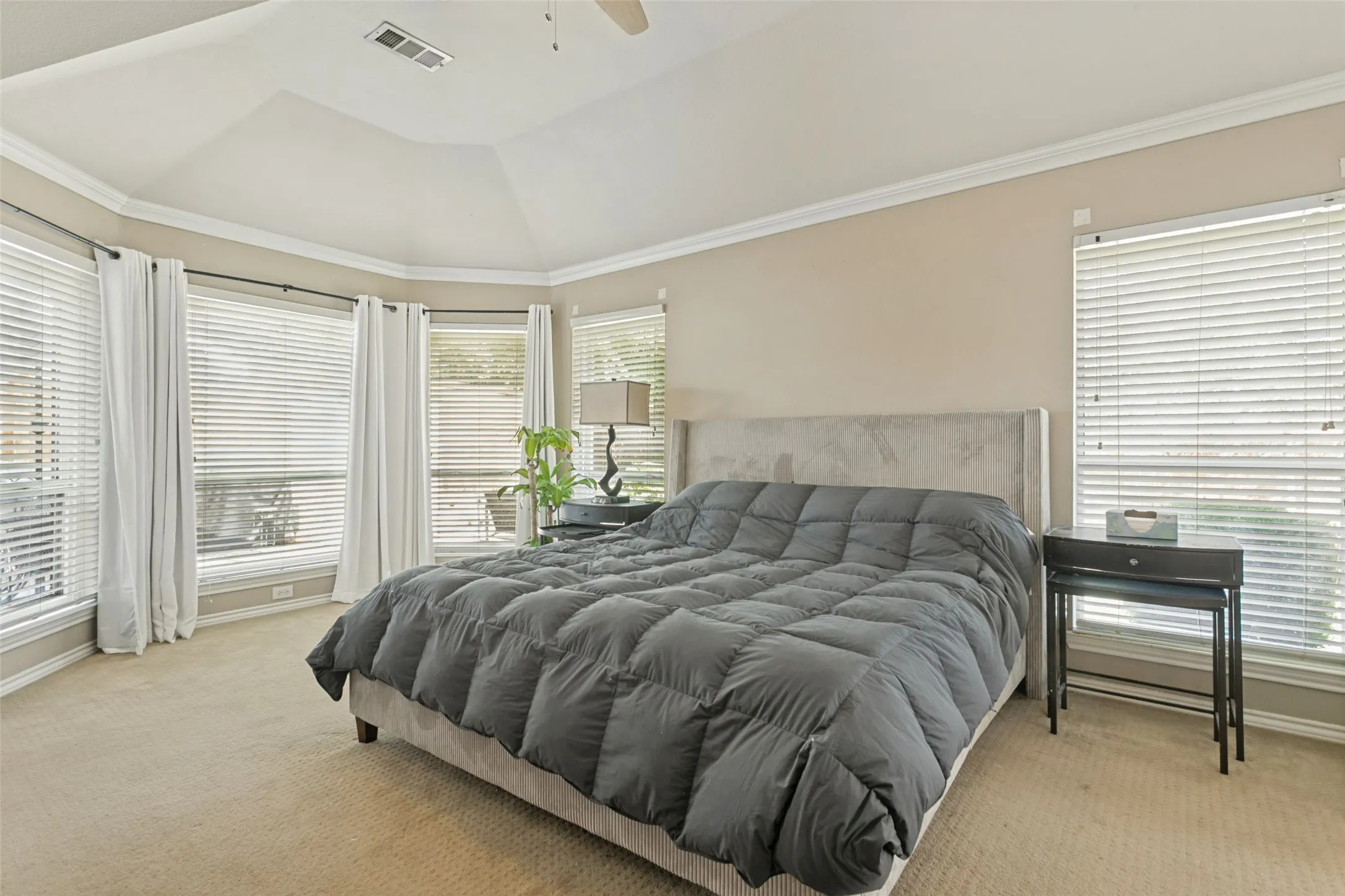 Vaulted ceiling with crown molding, carpet flooring, multiple windows with blinds, and recessed lighting