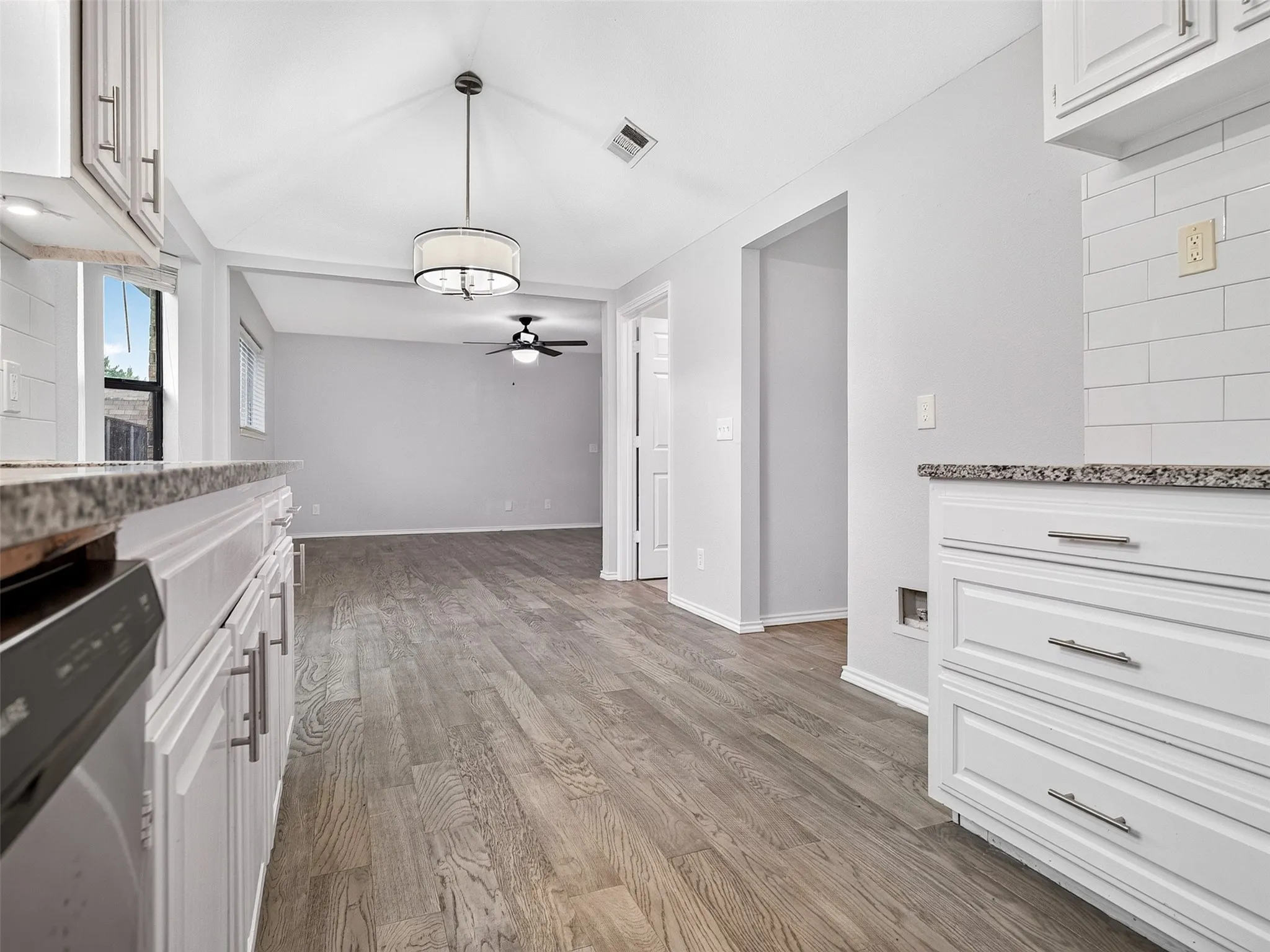 White cabinetry with brushed nickel hardware, speckled countertops, and a subway tile backsplash