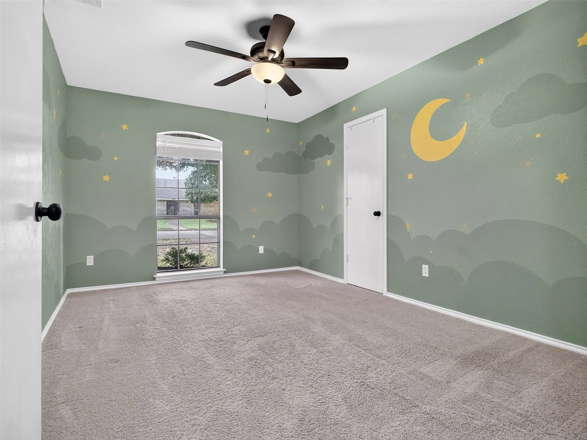 Arched window, ceiling fan with integrated lighting, wall-to-wall carpeting, and painted walls