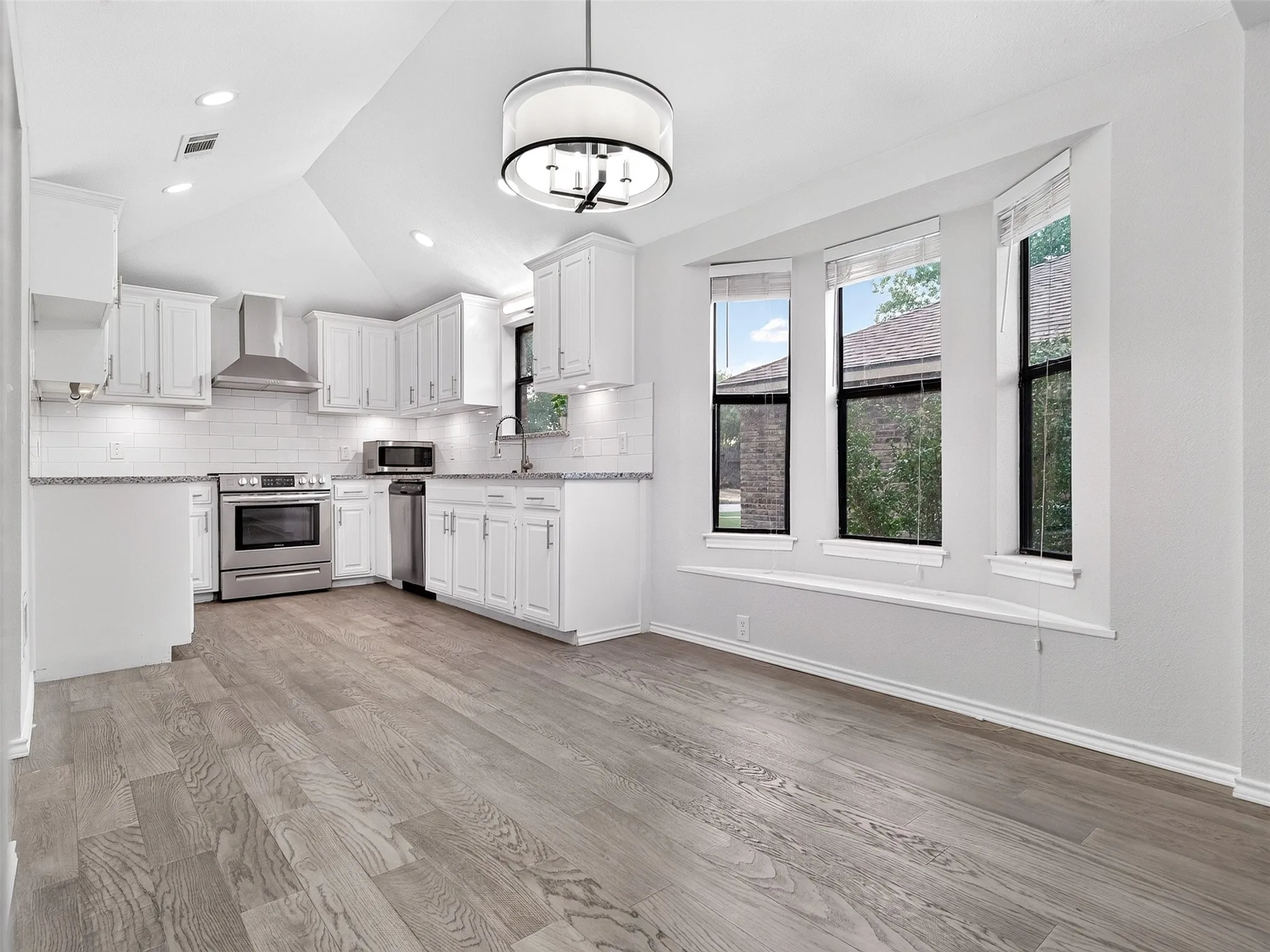 Kitchen featuring white cabinetry, stainless steel appliances, white subway tile backsplash, and light-toned wood-finish flooring