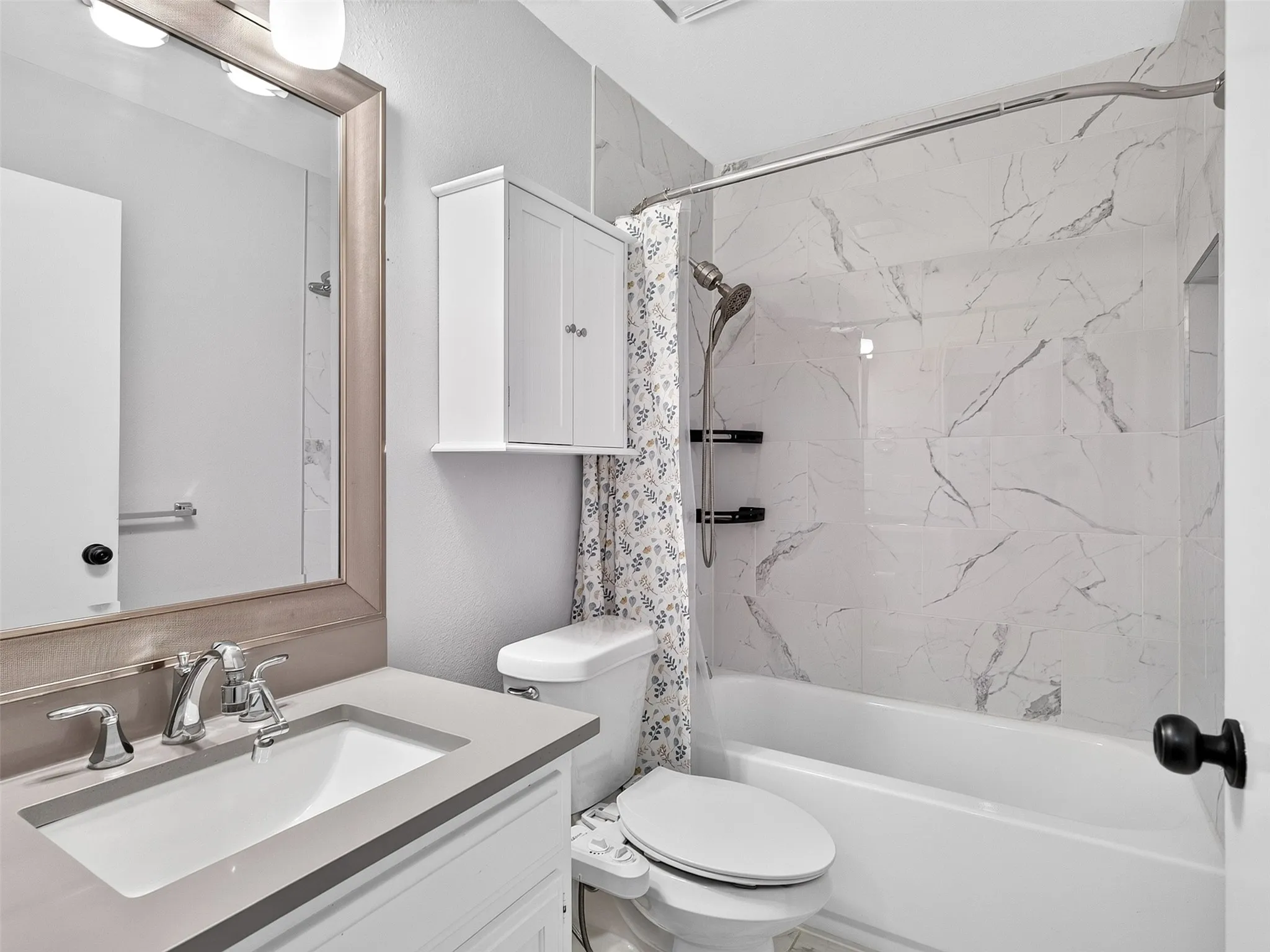 Vanity with integrated sink and chrome fixtures, quartz countertop, framed mirror, and built-in medicine cabinet