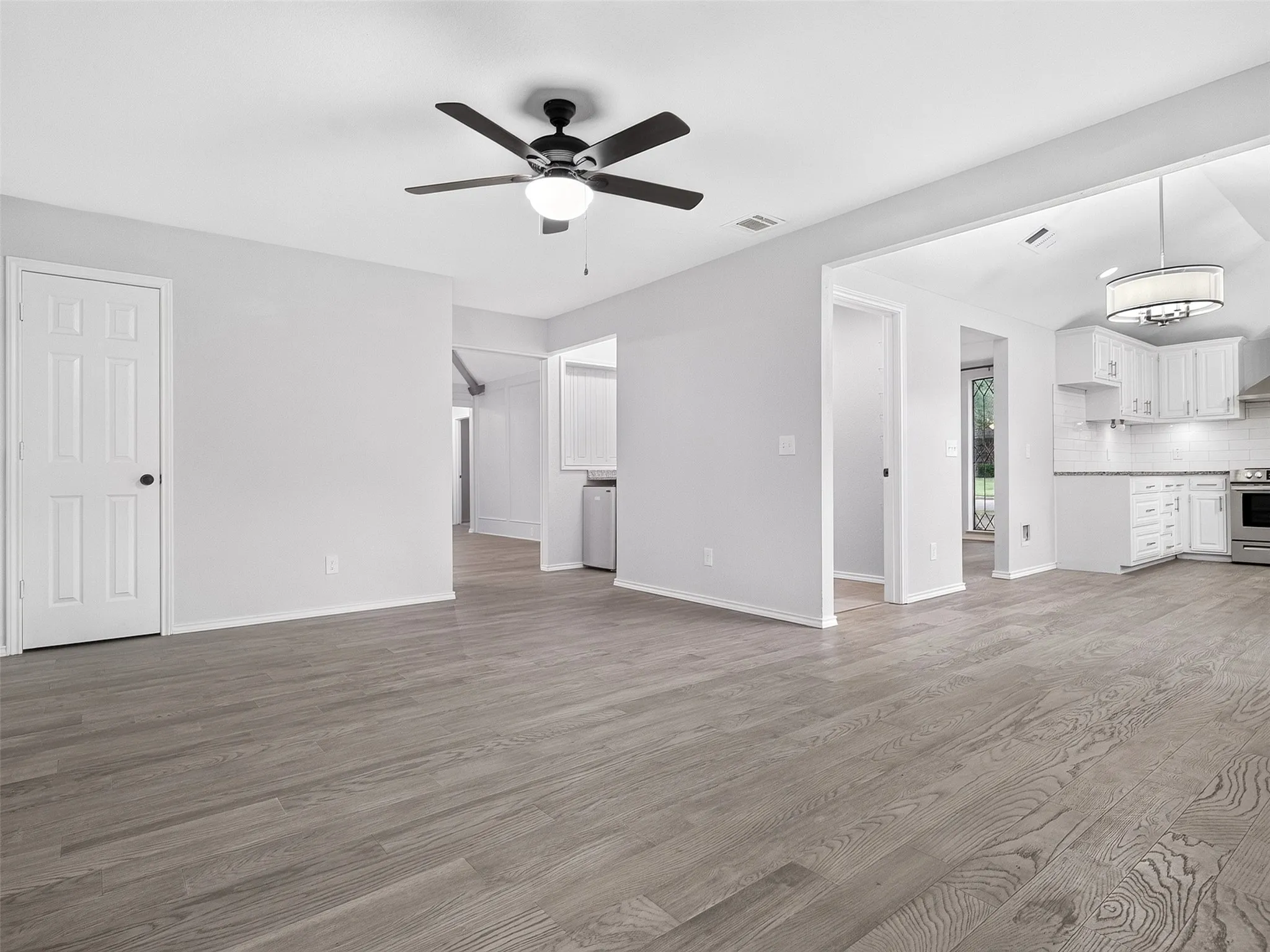 Wood-finish flooring throughout, paired with a ceiling fan and recessed lighting