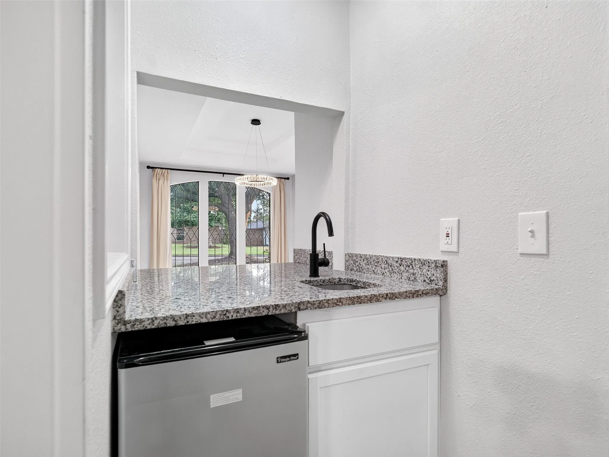 Wet bar featuring a granite countertop, undermount sink, and matte black faucet