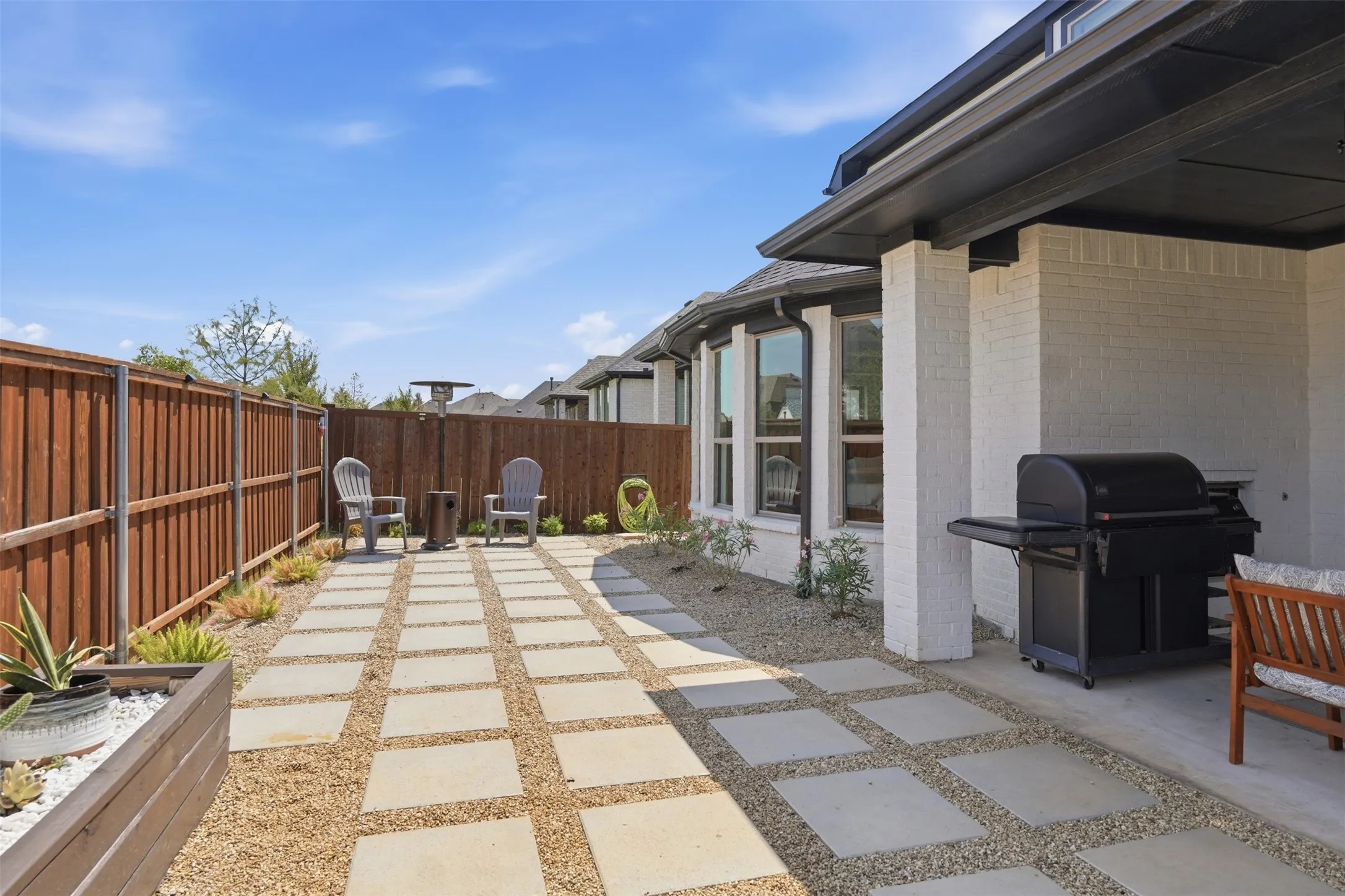 Paved patio with concrete pavers and gravel, featuring a wood privacy fence and a built-in planter
