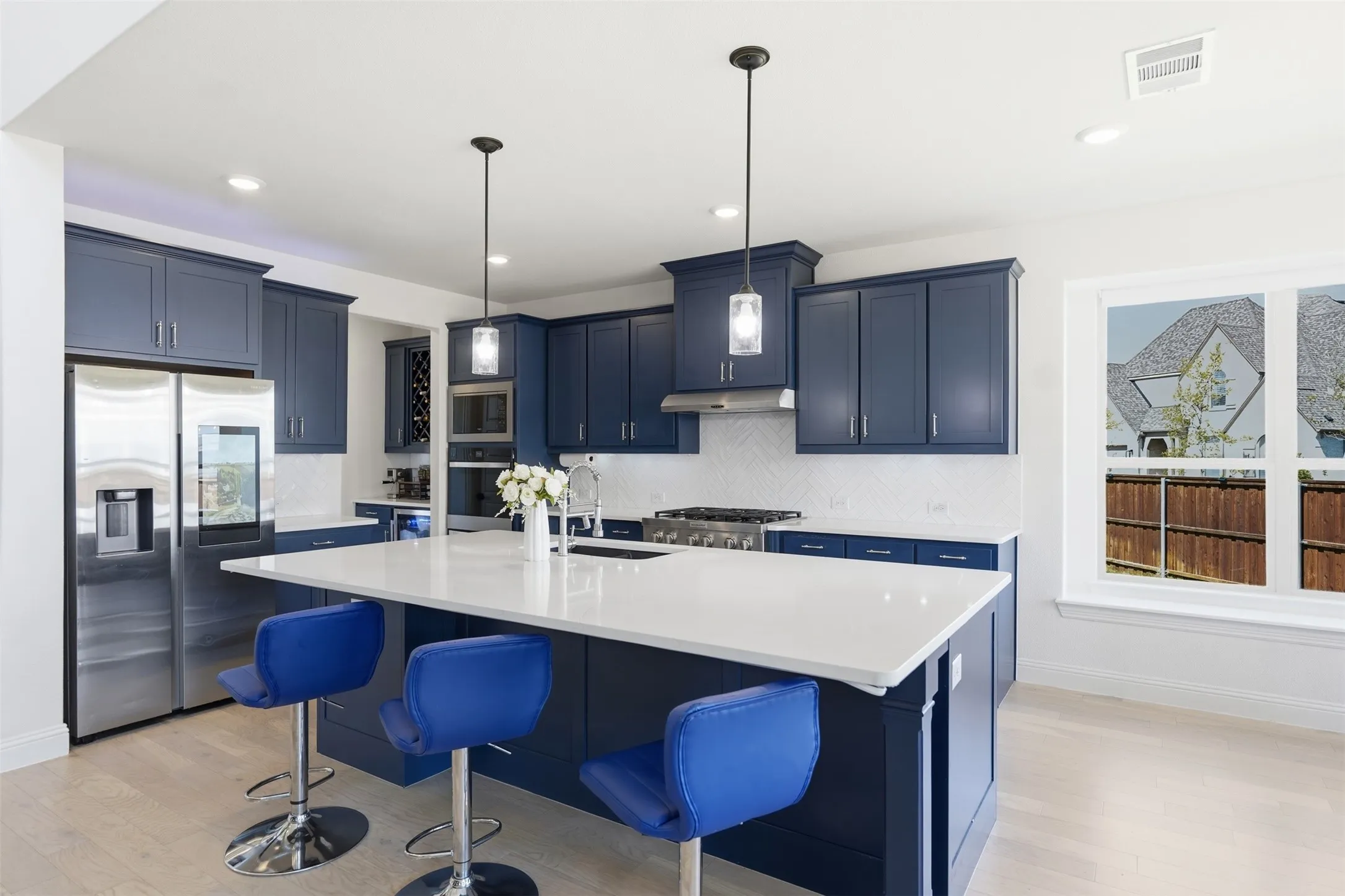 Kitchen featuring blue cabinetry, white countertops, stainless steel appliances, a white tile backsplash, and light wood-finish flooring