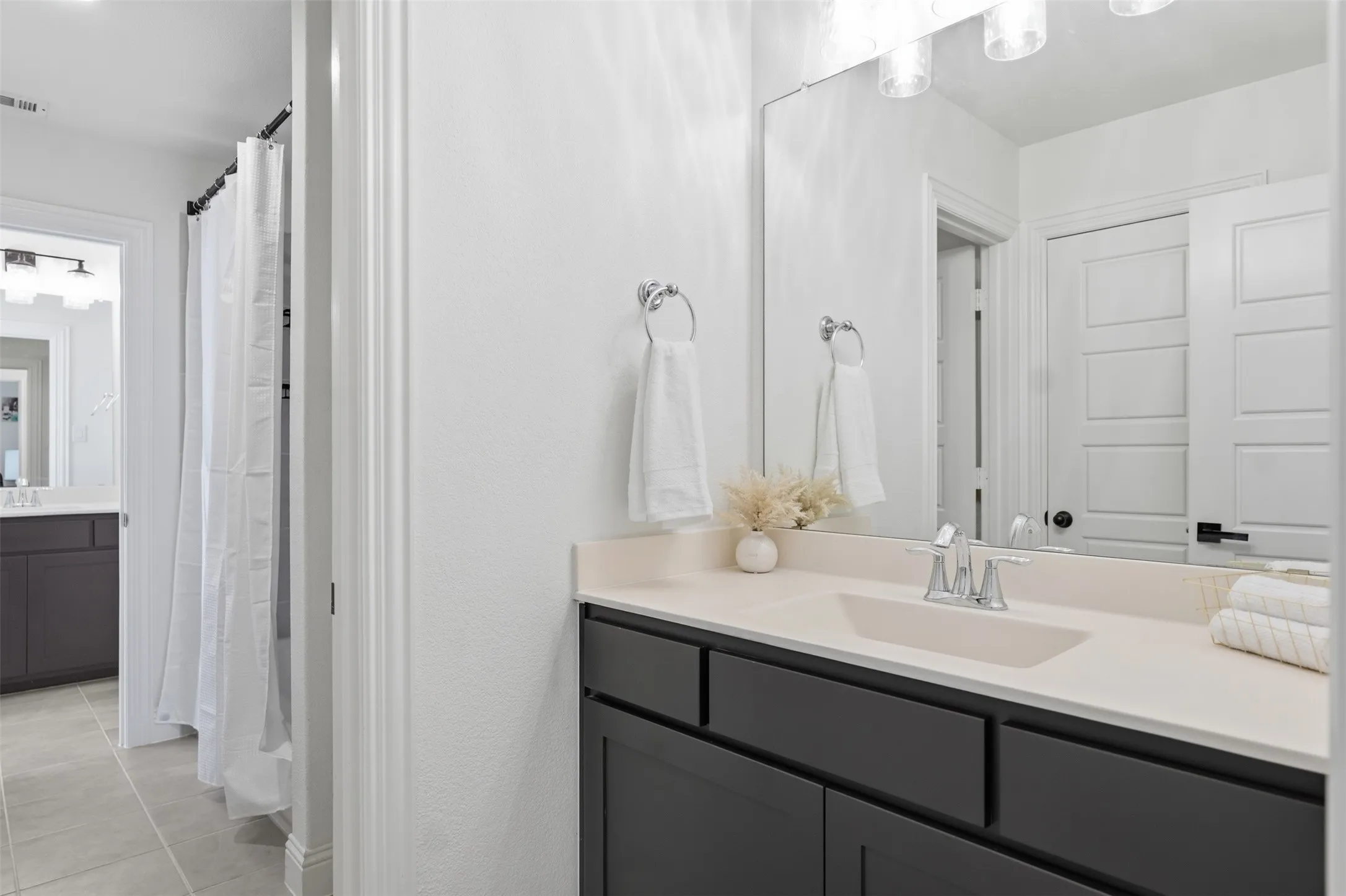 Jack & Jill Bathroom between bedrooms - Dual vanity areas featuring dark cabinetry and light countertops