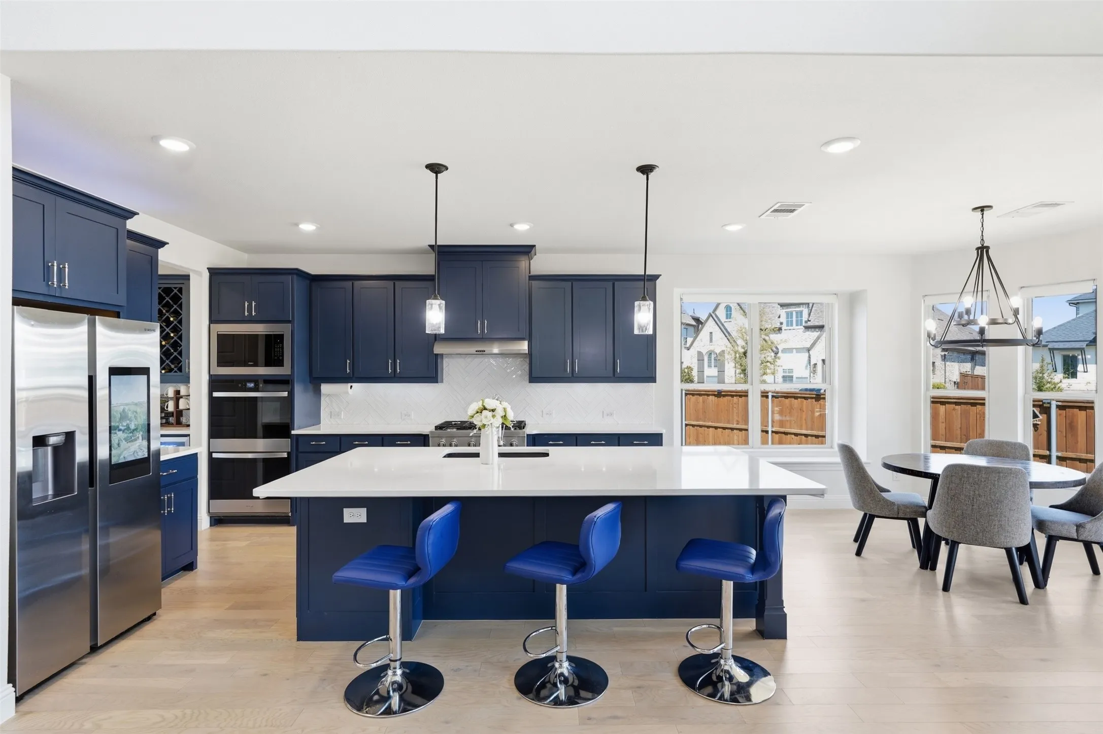 Kitchen featuring blue cabinetry, stainless steel appliances, a center island with a white countertop, and wood-finish flooring