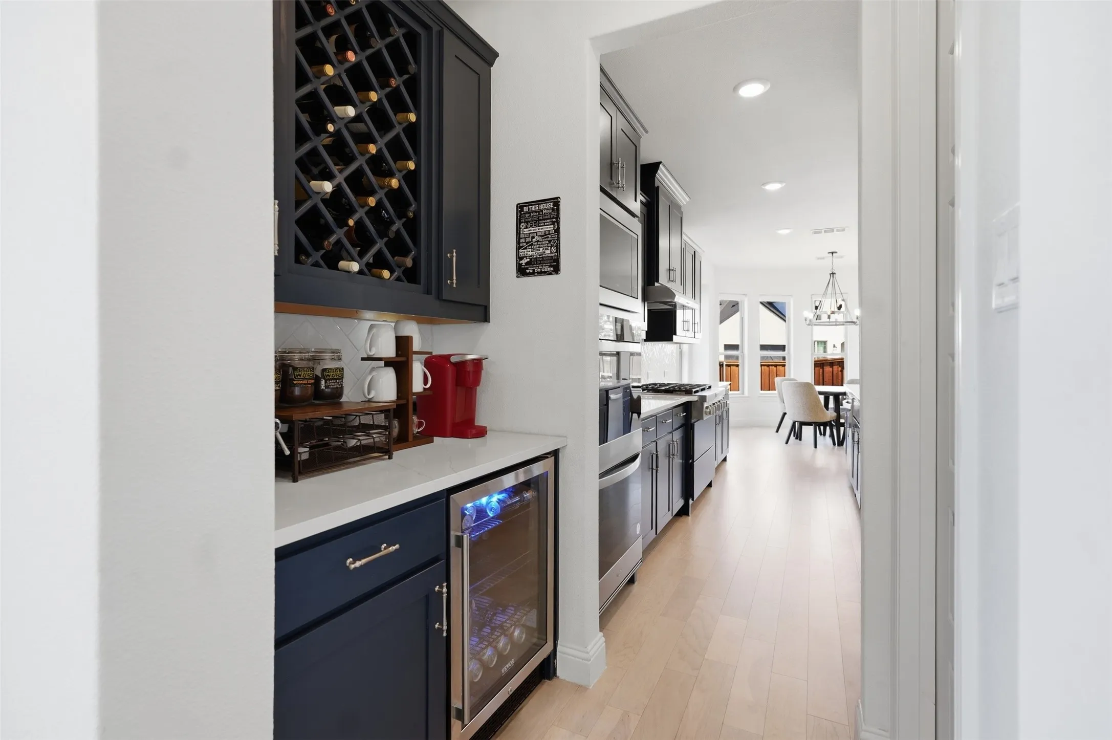 Built-in wine rack, beverage cooler, dark wood-finish cabinetry, light wood-finish flooring, and recessed lighting