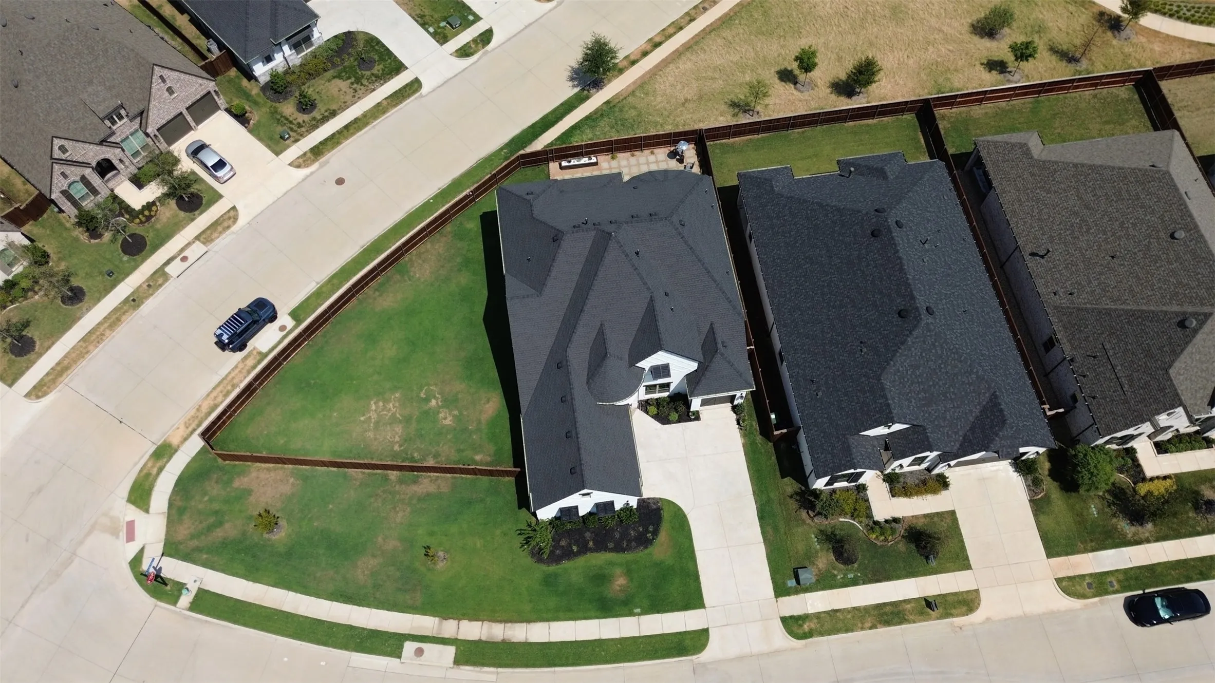 Expansive lot with manicured lawn, established landscaping, and dark asphalt shingle roofing