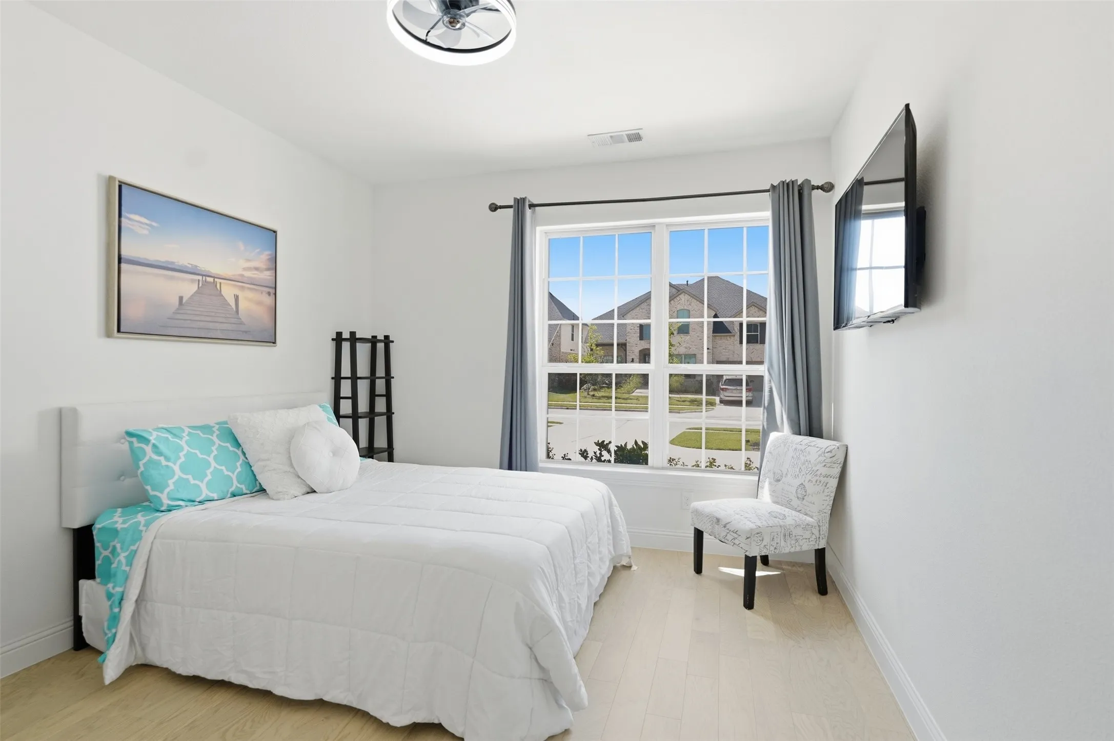 Bedroom 2 - Downstairs...Light wood-finish flooring, a multi-pane window, white walls, and a ceiling fan with integrated lighting