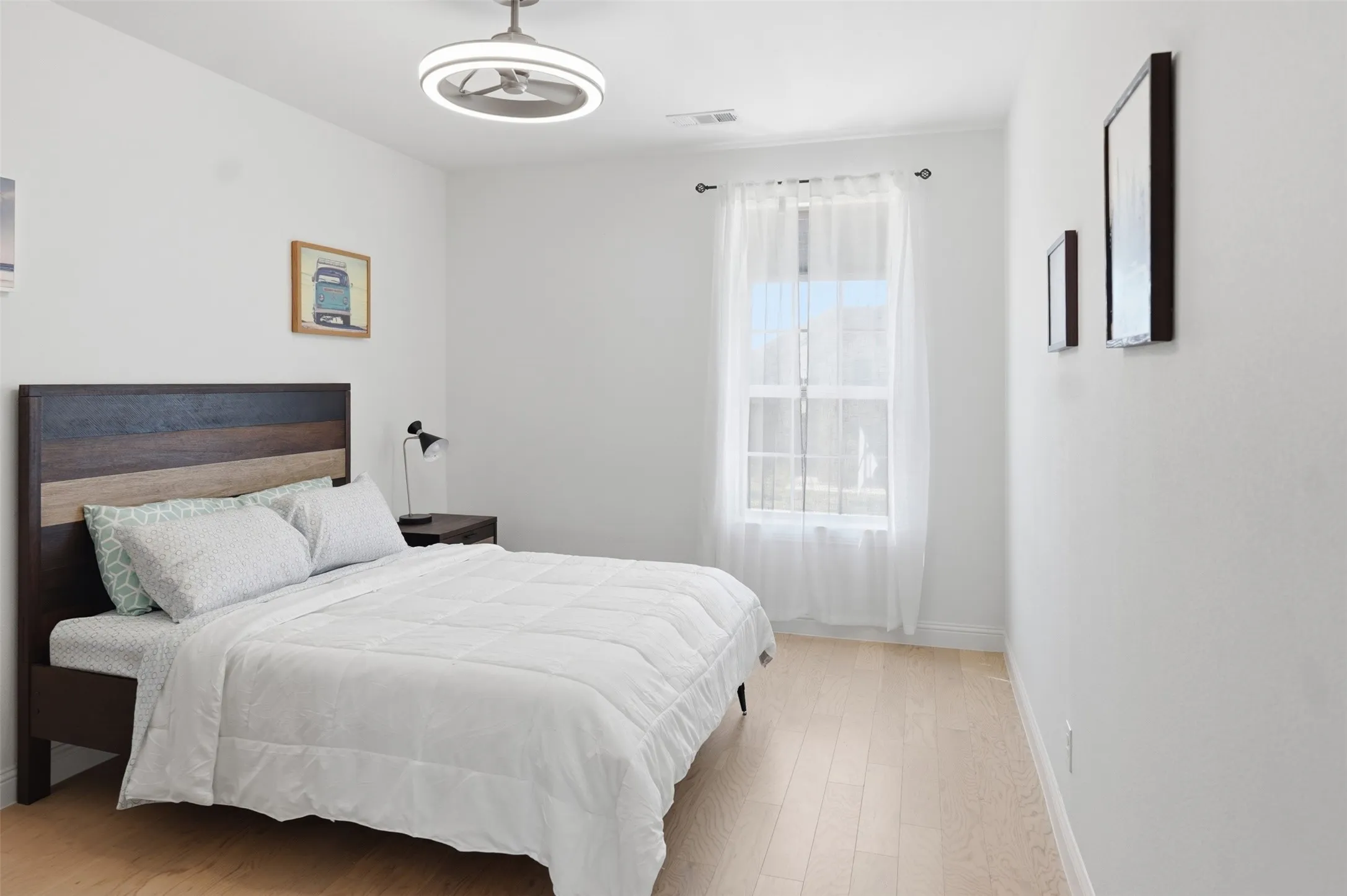 Bedroom 3 - Light wood-finish flooring, a contemporary ceiling fan, and a single window with sheer curtains