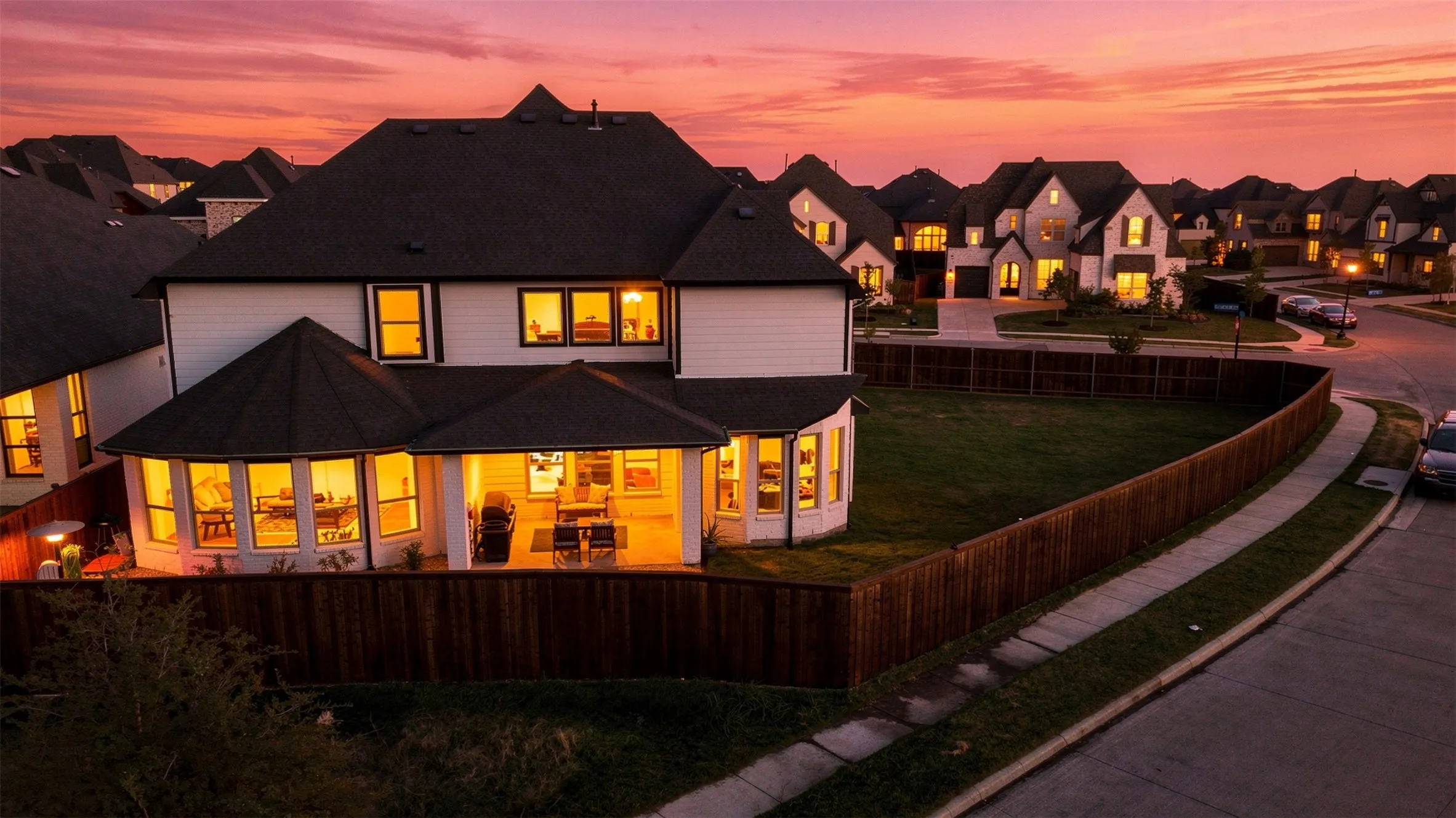 Expansive backyard featuring a manicured lawn, wood fencing, and a covered patio