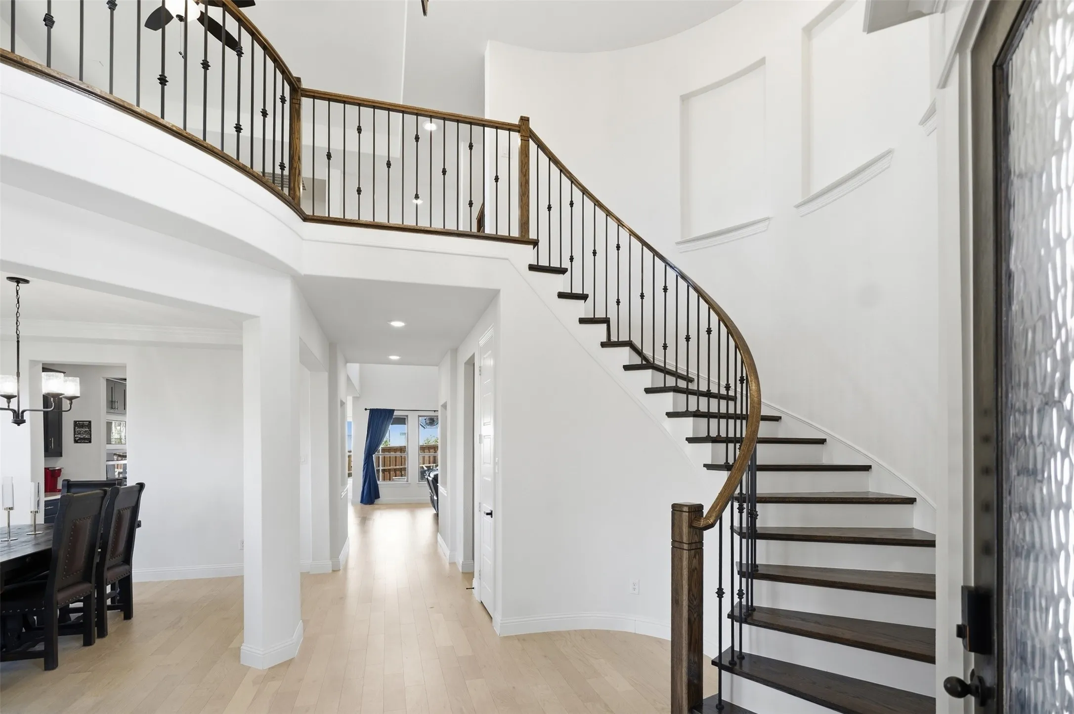 Grand curved staircase with dark wood treads, wrought iron balusters, and a wood handrail