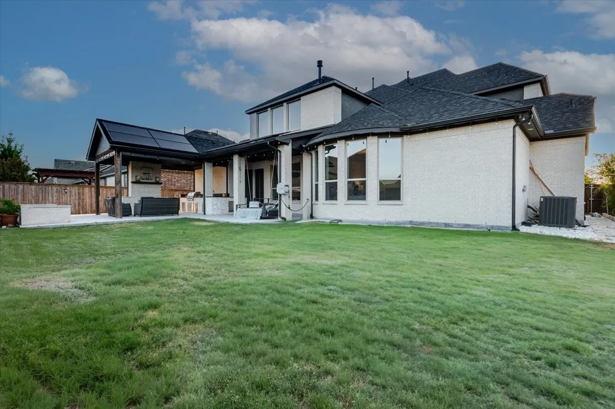 Extensive backyard with a covered patio featuring solar panels, an outdoor kitchen, and a built-in planter