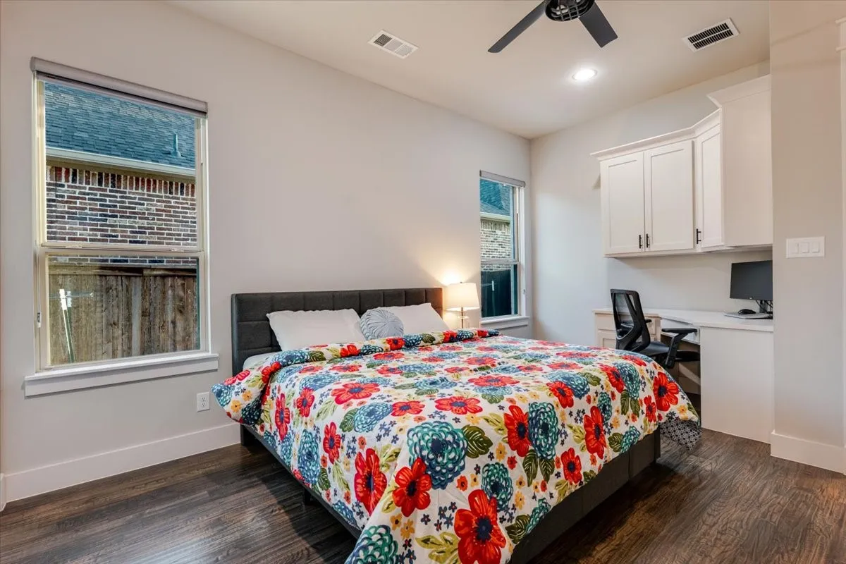 Wood-finish flooring, built-in desk, white cabinetry, recessed lighting, and a ceiling fan