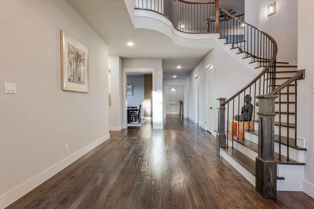 Hardwood flooring, curved staircase with wrought iron balusters, recessed lighting, and a neutral wall color