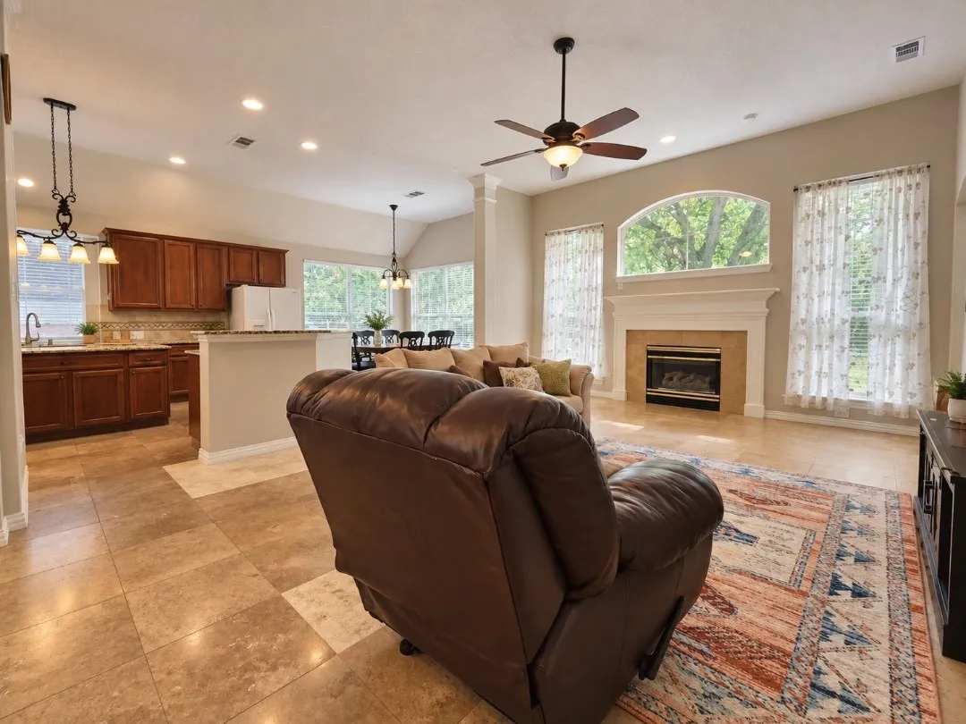 Open-concept living area featuring a fireplace with a mantel, vaulted ceilings, and tile flooring