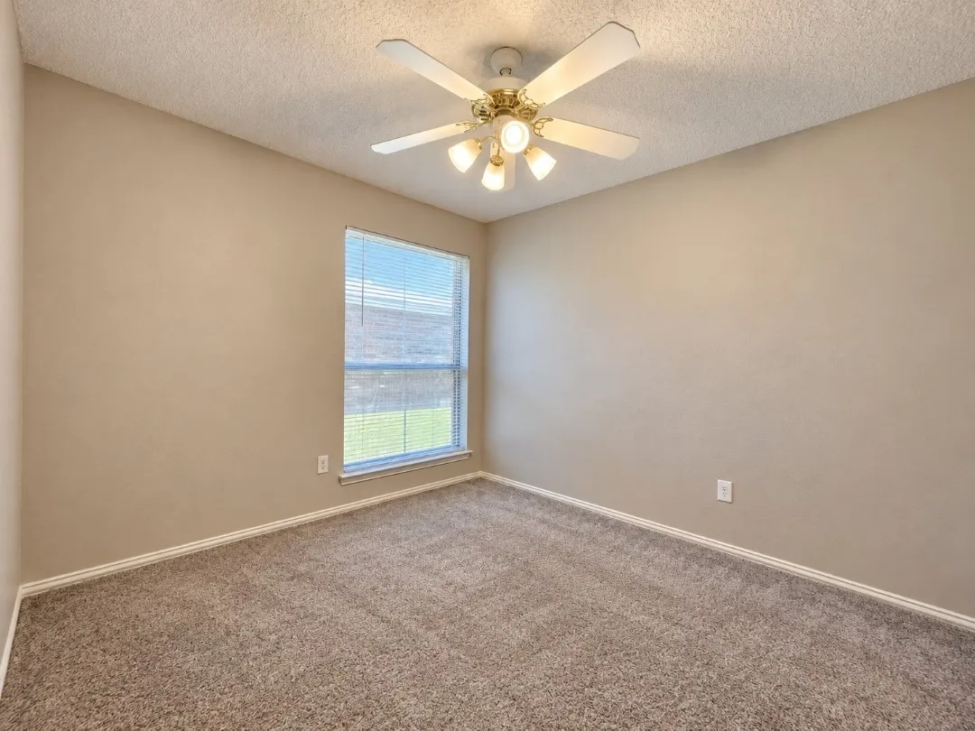 Textured ceiling with a ceiling fan light fixture, neutral tone walls, and carpet flooring