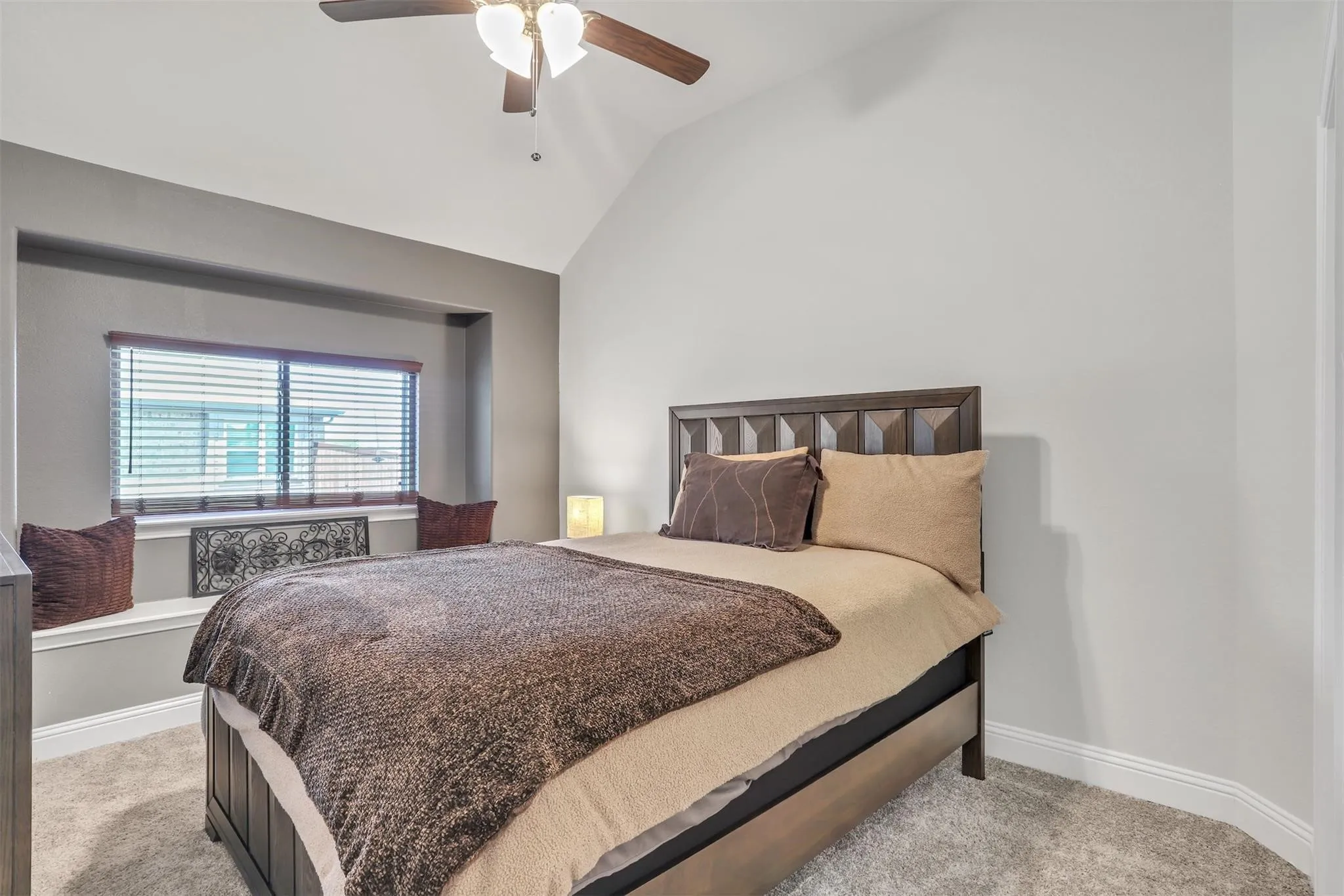 Vaulted ceiling with a ceiling fan, recessed window alcove with a built-in bench, and carpet flooring