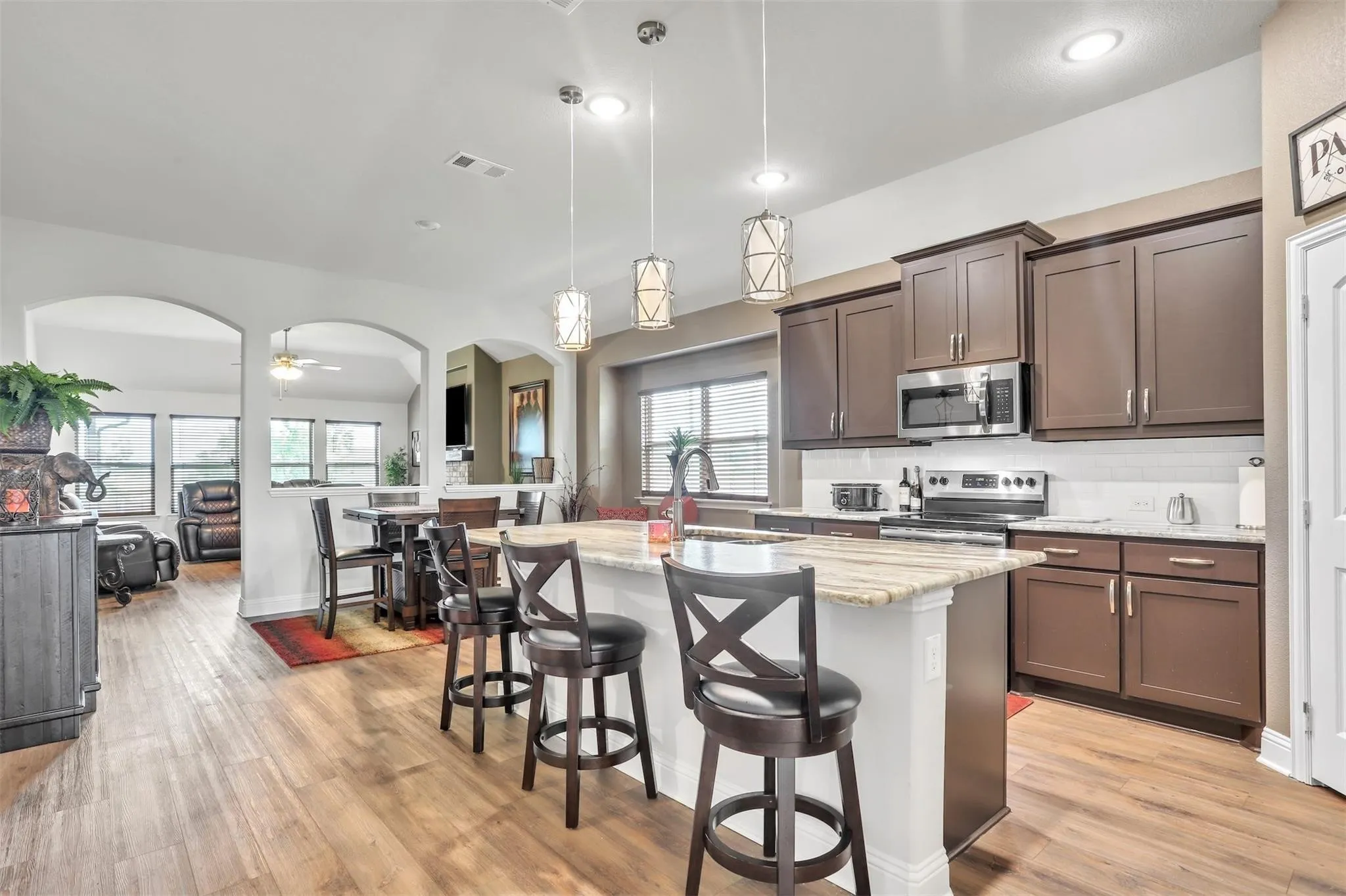 Kitchen with wood-finish flooring, dark wood cabinetry, stainless steel appliances, and a central island with bar seating