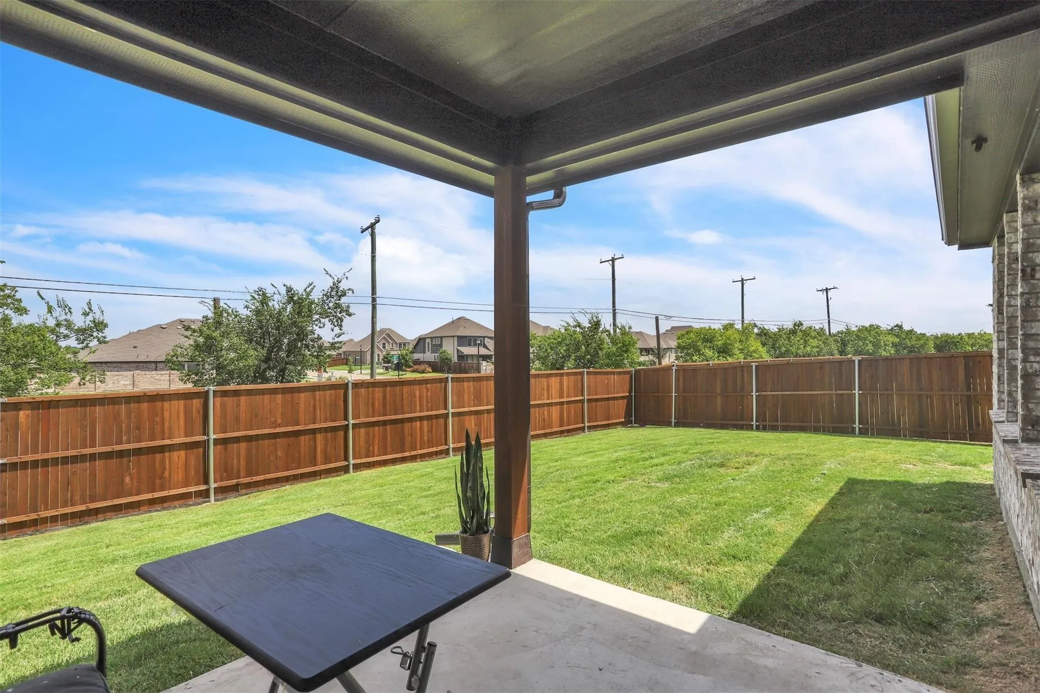 Covered patio with concrete flooring, wood-finish support column, and a brick-finish exterior wall