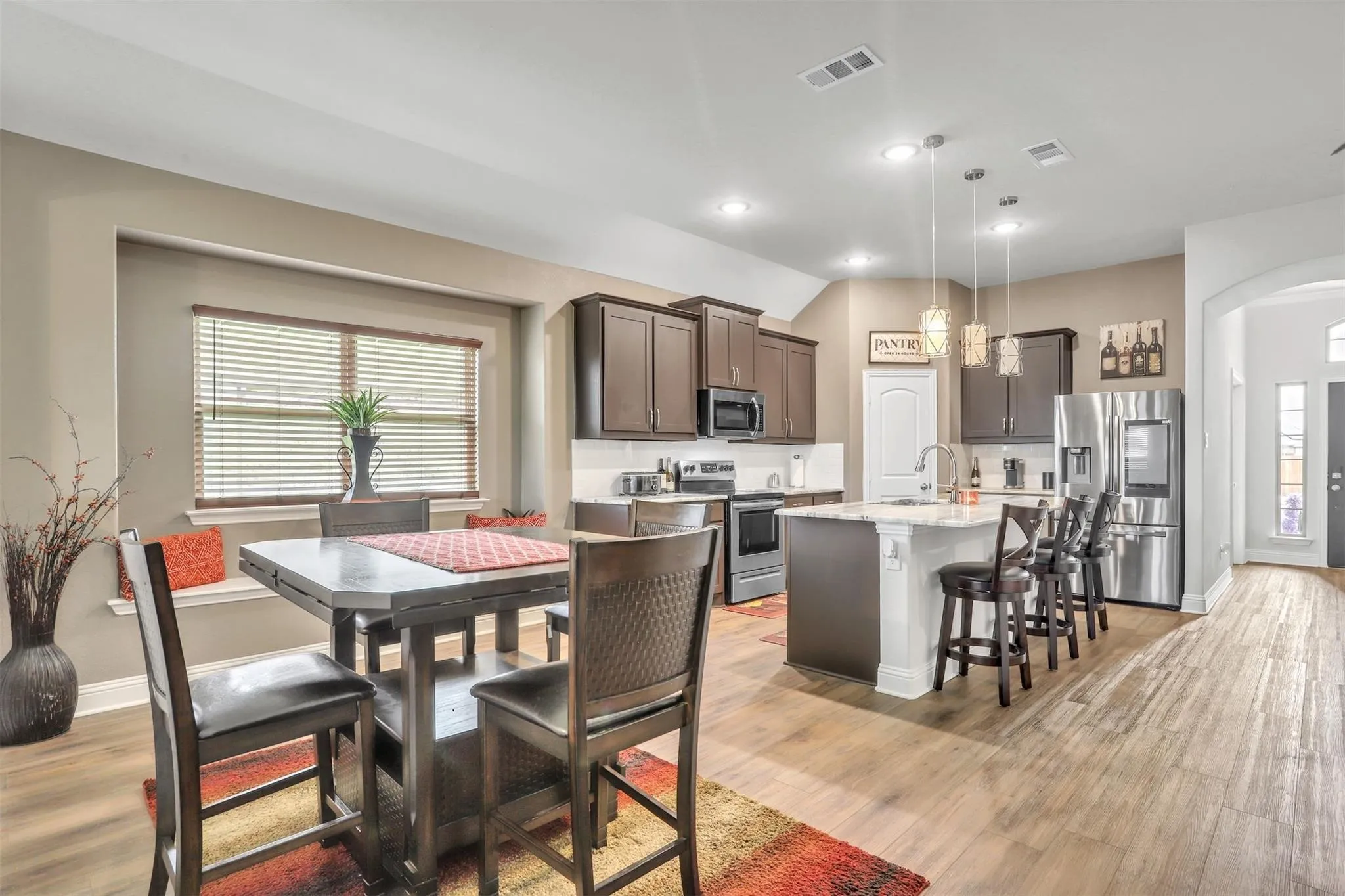 Kitchen featuring wood-finish flooring, dark wood cabinetry, a center island with seating, stainless steel appliances, and recessed lighting