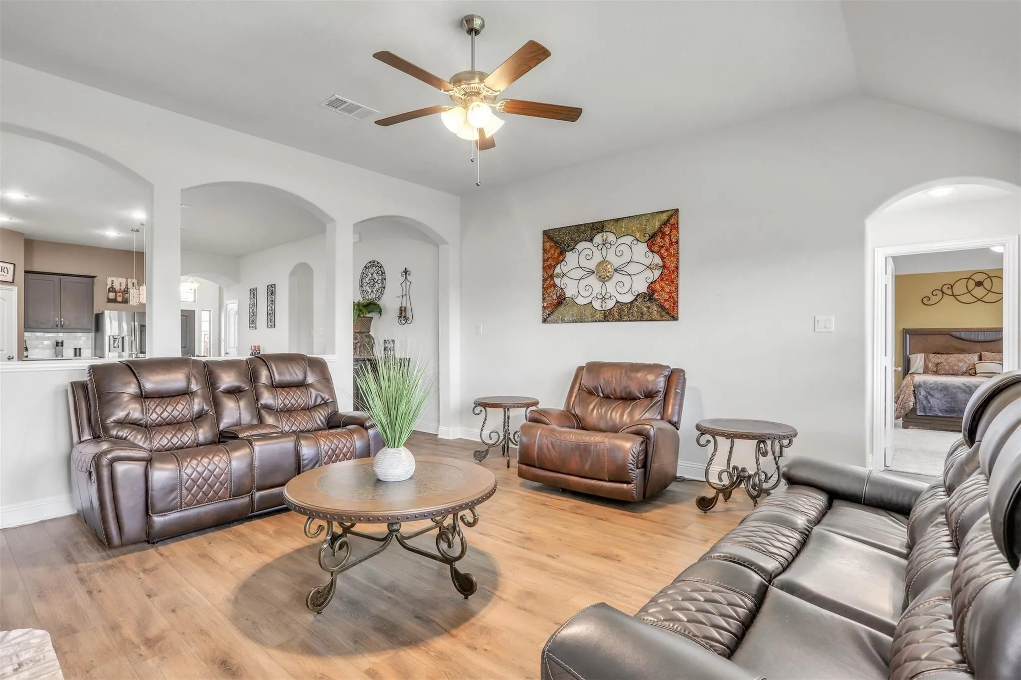 Vaulted ceiling with a ceiling fan, wood-finish flooring, and arched architectural openings