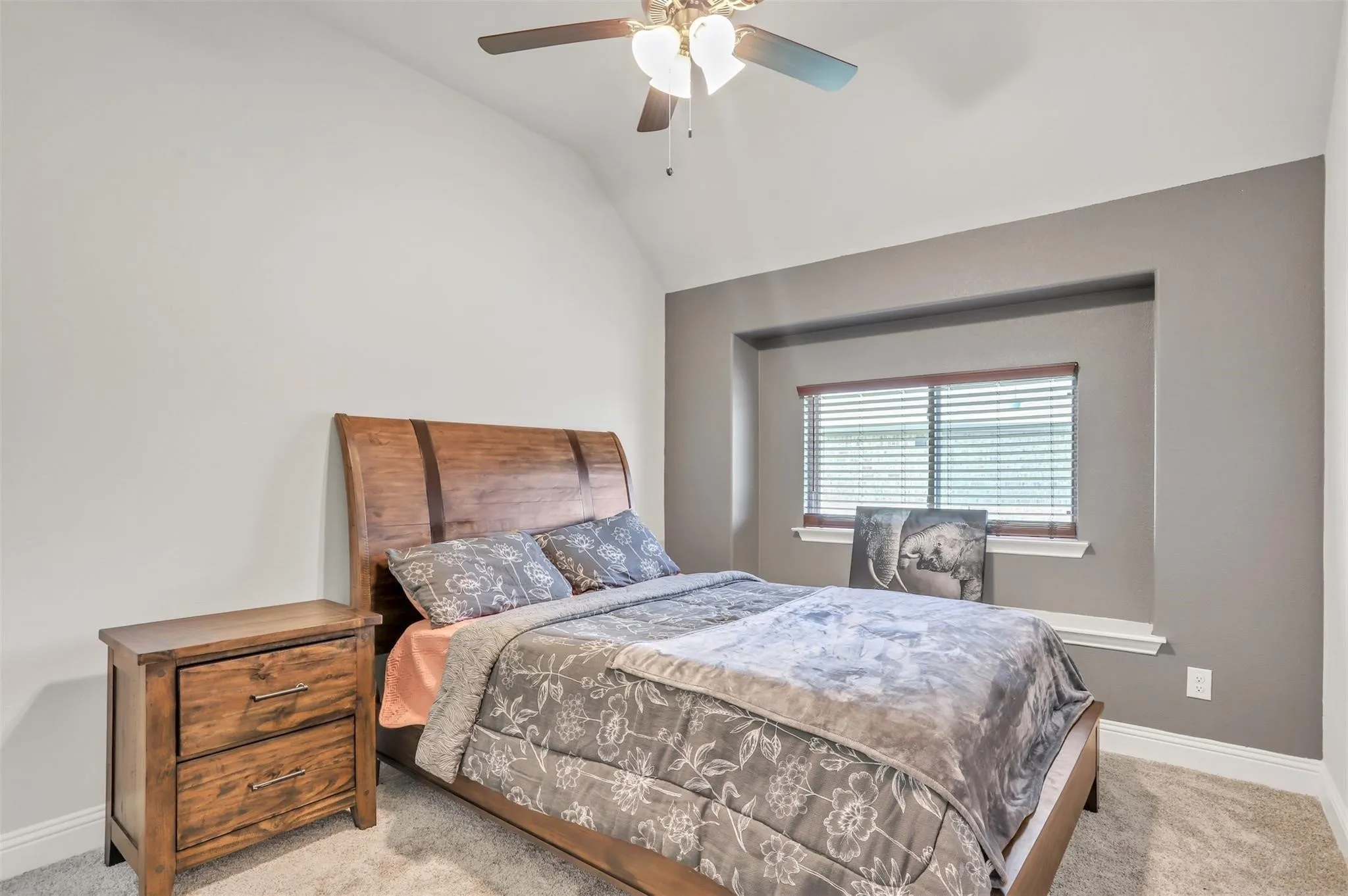 Vaulted ceiling, ceiling fan with integrated lighting, window with blinds, window sill, and carpet flooring