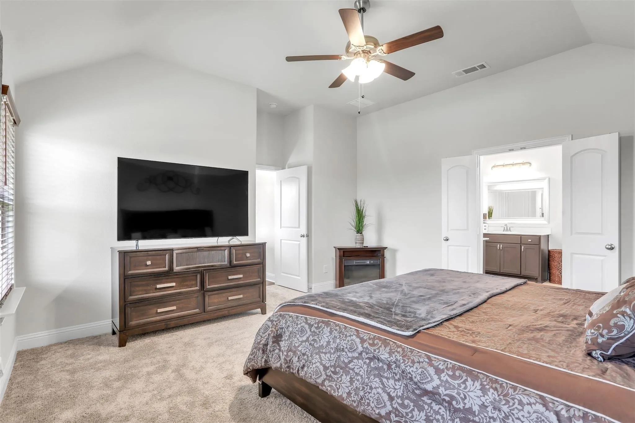 Vaulted ceiling with a ceiling fan, carpeted flooring, and a large window with blinds