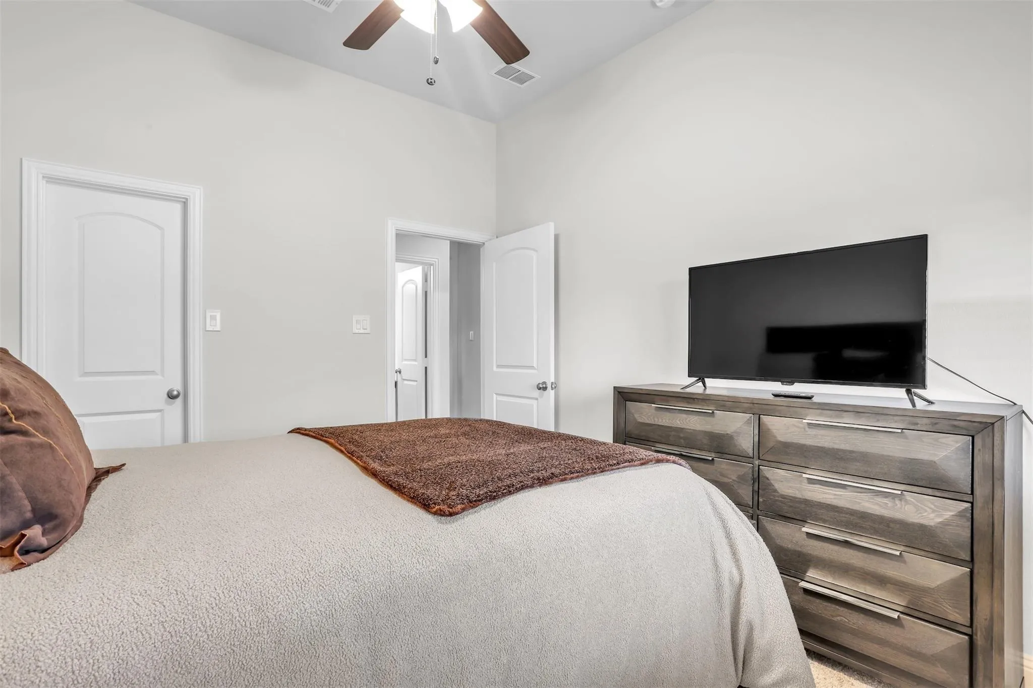 Vaulted ceiling, ceiling fan with light fixture, white interior doors, light-colored walls, and carpeting