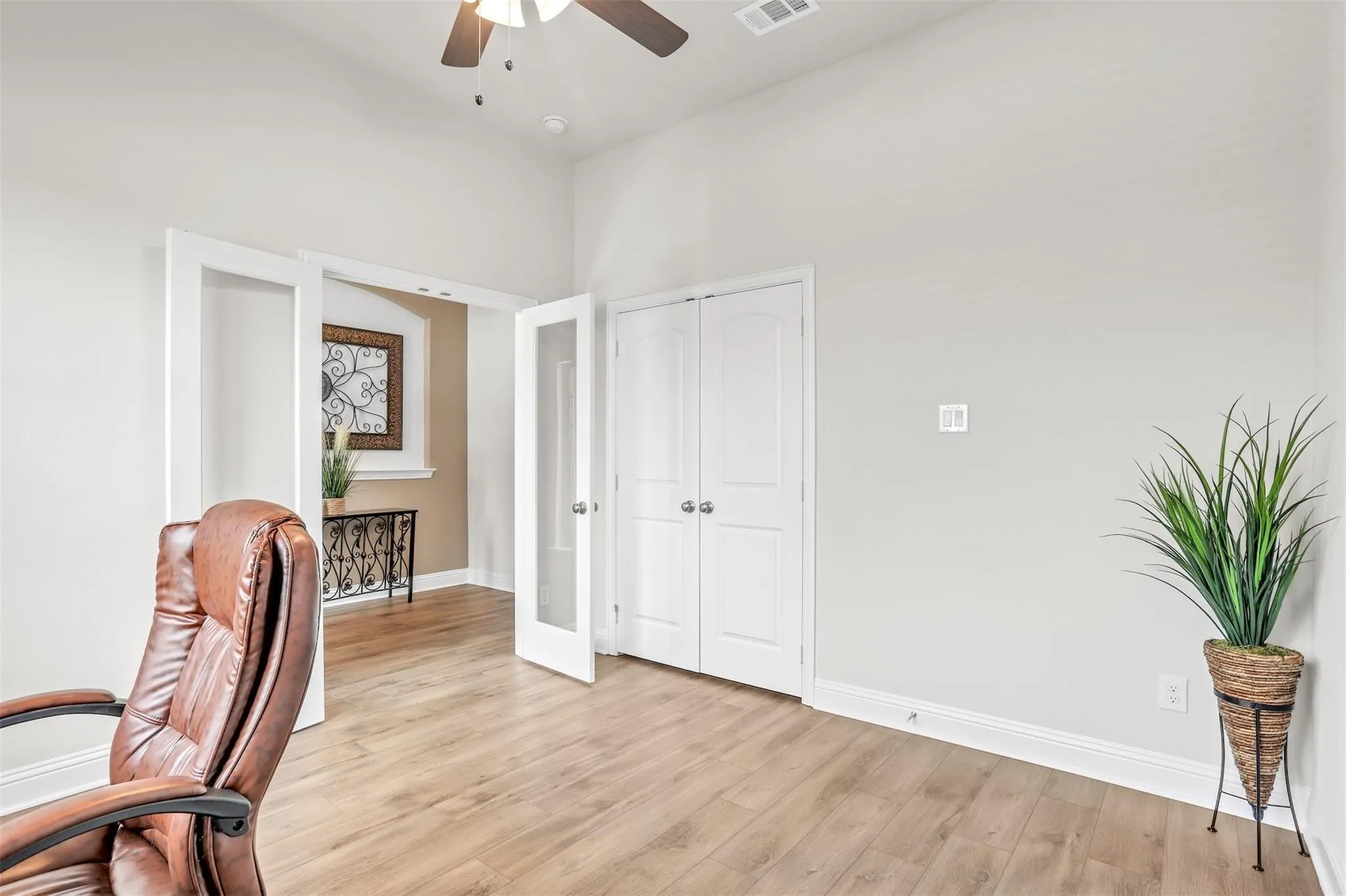 Wood-finish flooring, white trim, recessed lighting, ceiling fan, and French doors