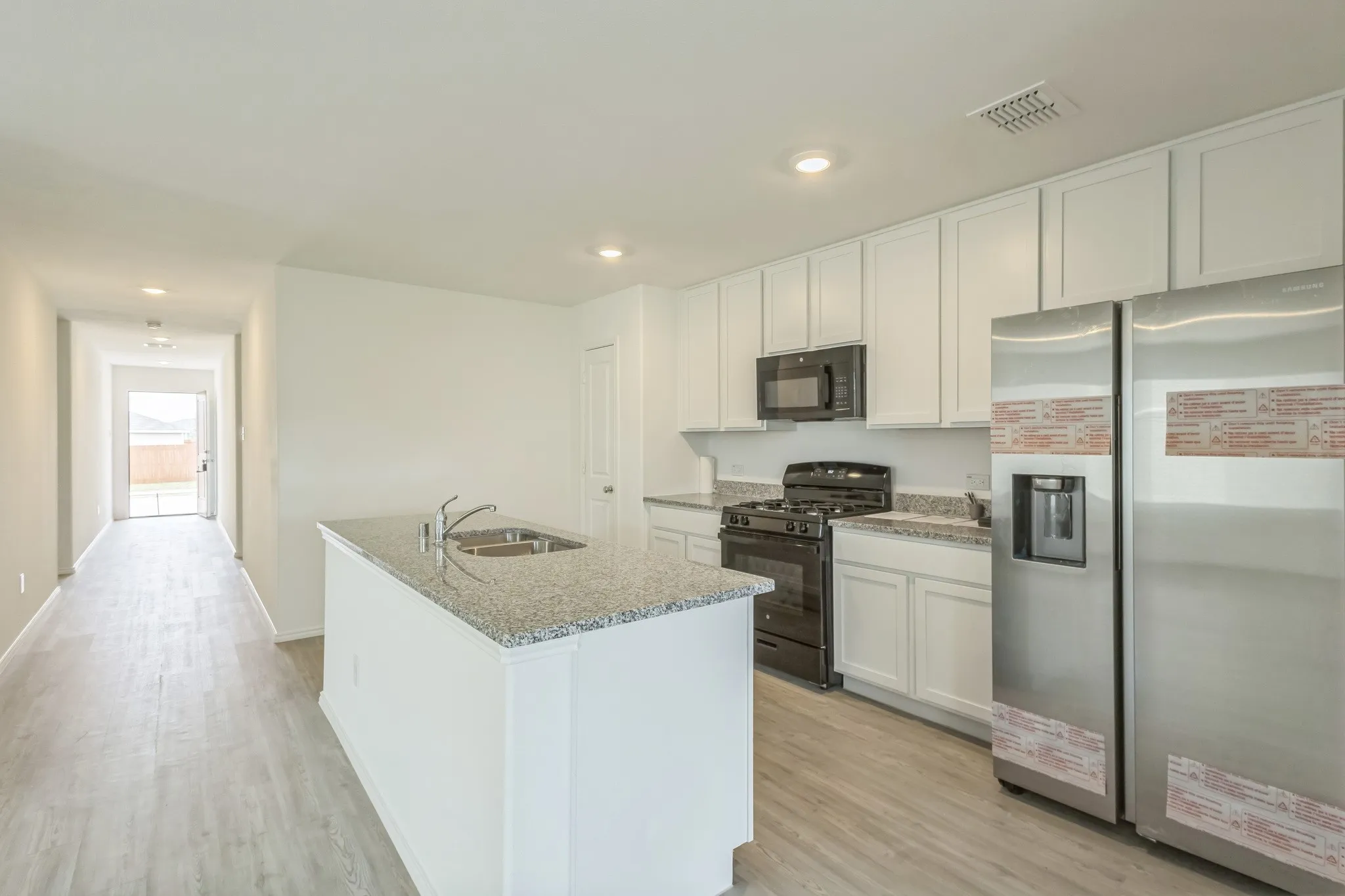 Kitchen featuring white cabinetry, granite countertops, stainless steel appliances, and a central island with an undermount sink