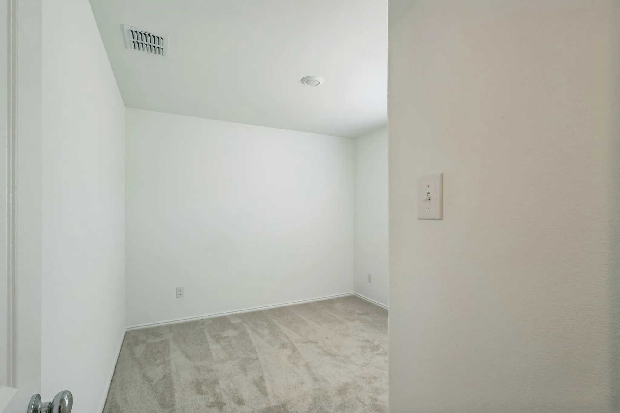 Neutral wall colors, recessed ceiling lighting, and carpet flooring