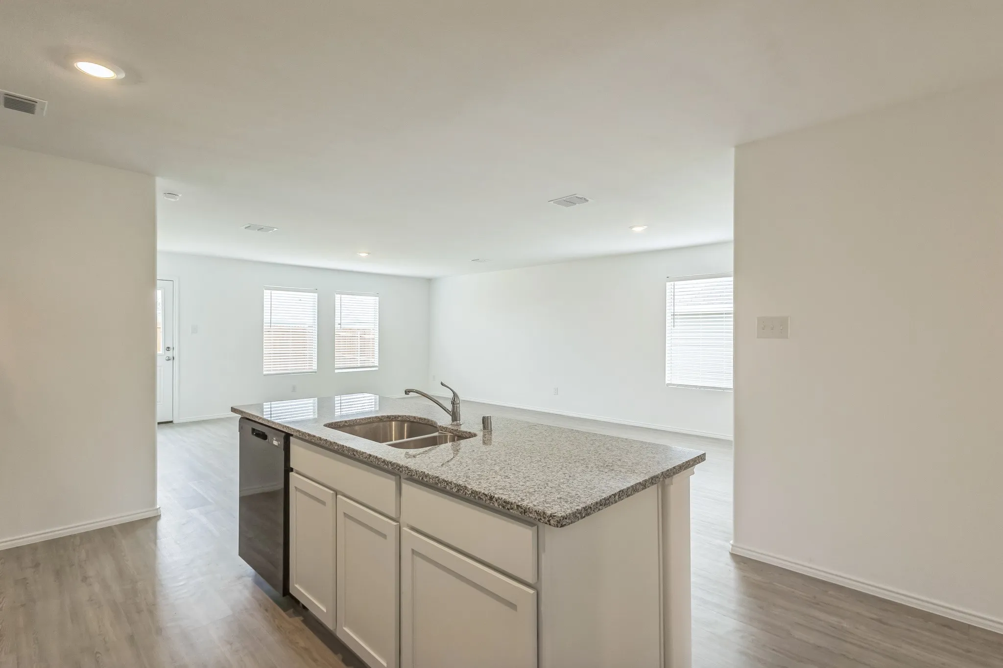 Kitchen island with a double basin sink, chrome faucet, and stone countertop
