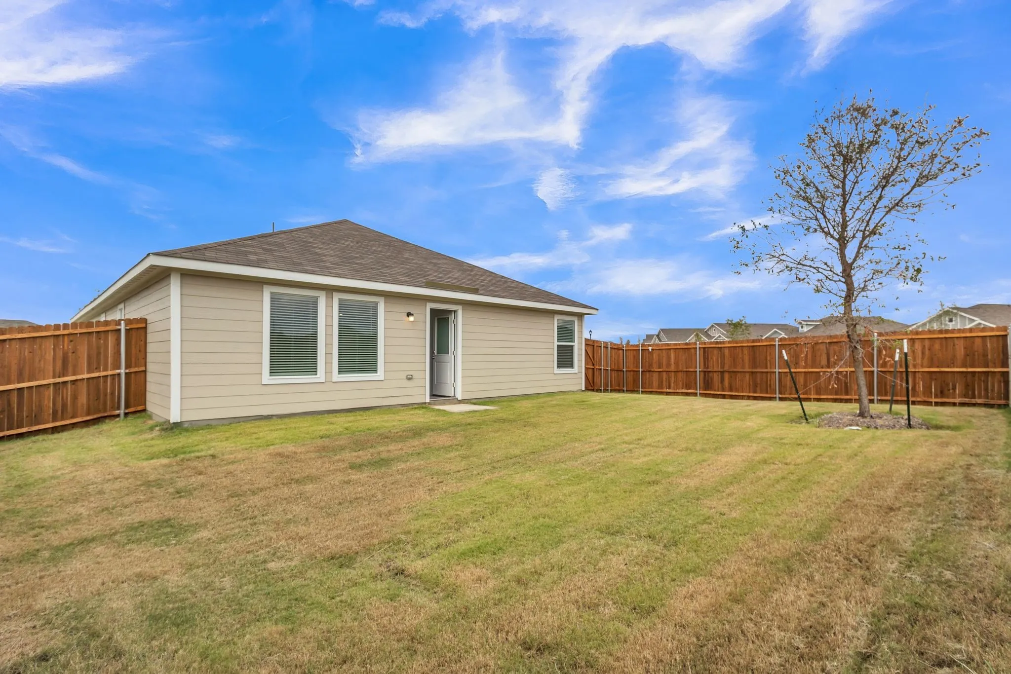 Expansive backyard featuring a new privacy fence, mature trees, a well-maintained lawn, and a neutral-toned exterior