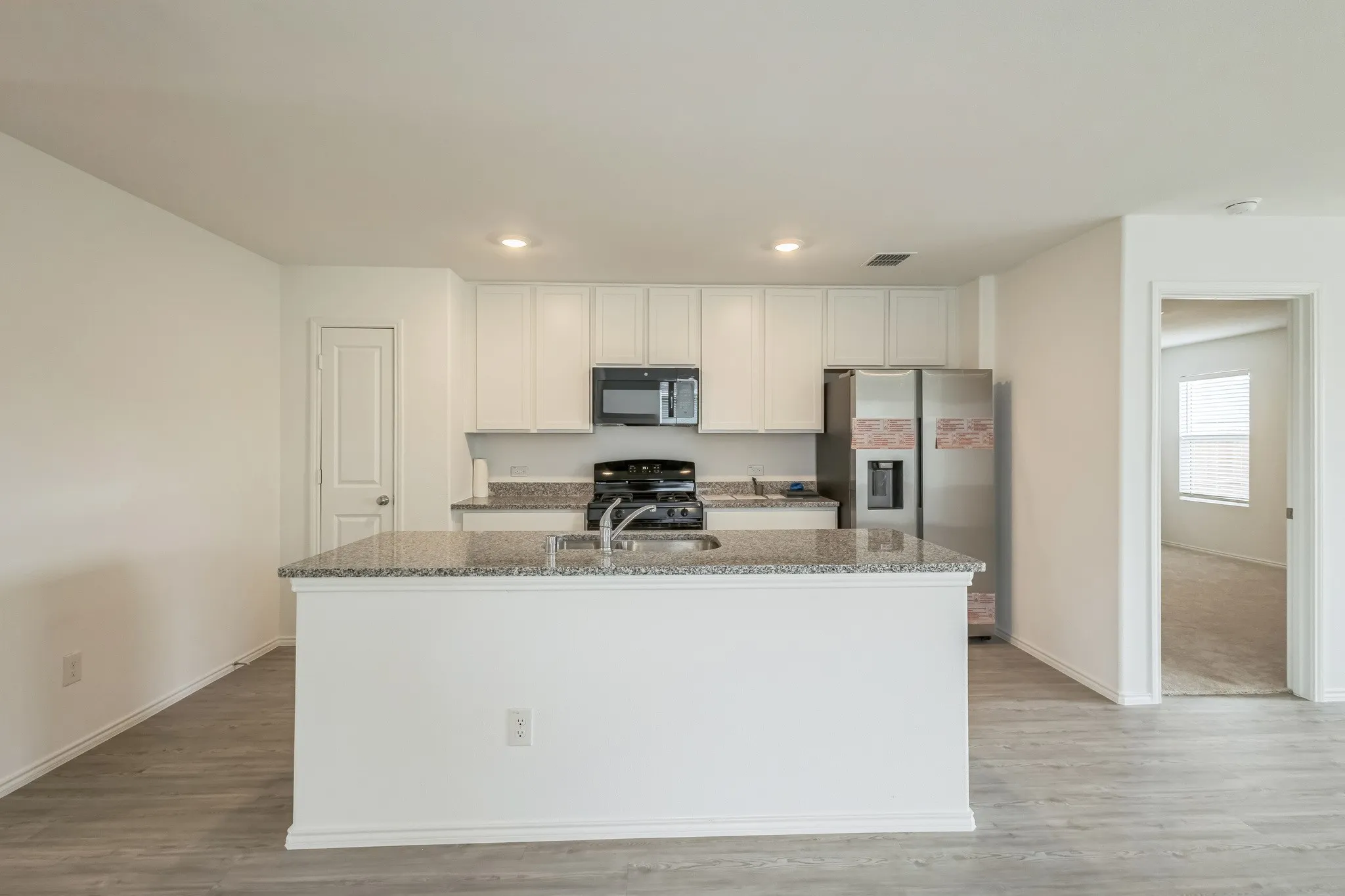 Kitchen featuring white cabinetry, granite countertops, an undermount sink, and stainless steel appliances
