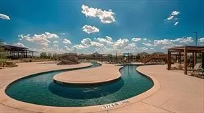 Curved waterway with surrounding hardscaping, a wooden bridge, and pergolas