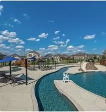 Resort-style pool area featuring a lazy river, water slide, and shaded lounge spaces