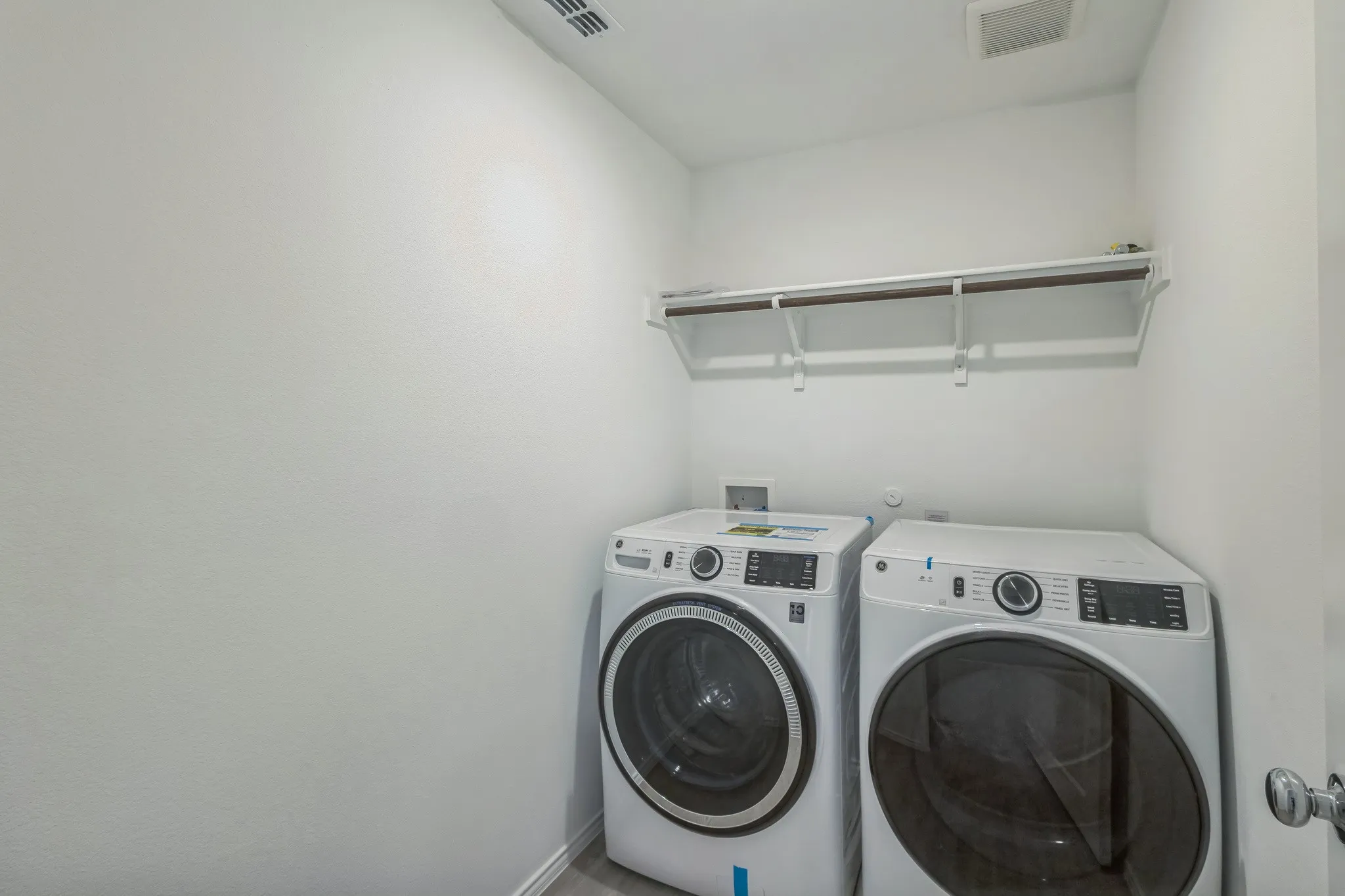 Dedicated laundry space with a built-in white shelf and hanging rod