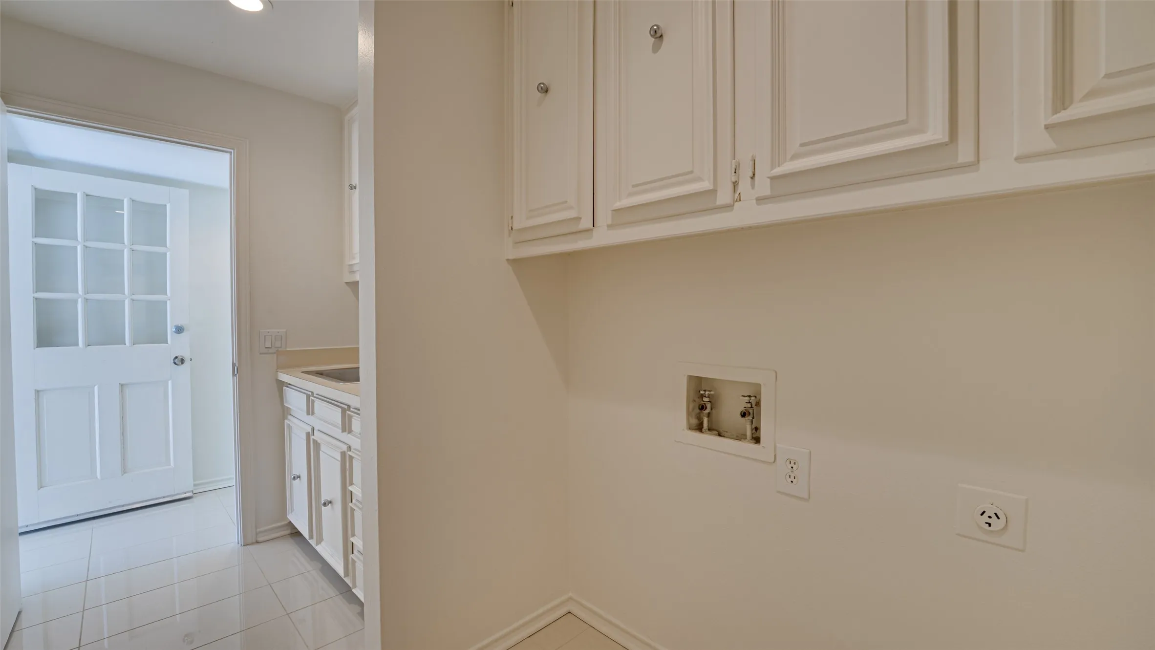 Clothes washing area featuring light tile patterned flooring, hookup for an electric dryer, cabinets, and hookup for a washing machine
