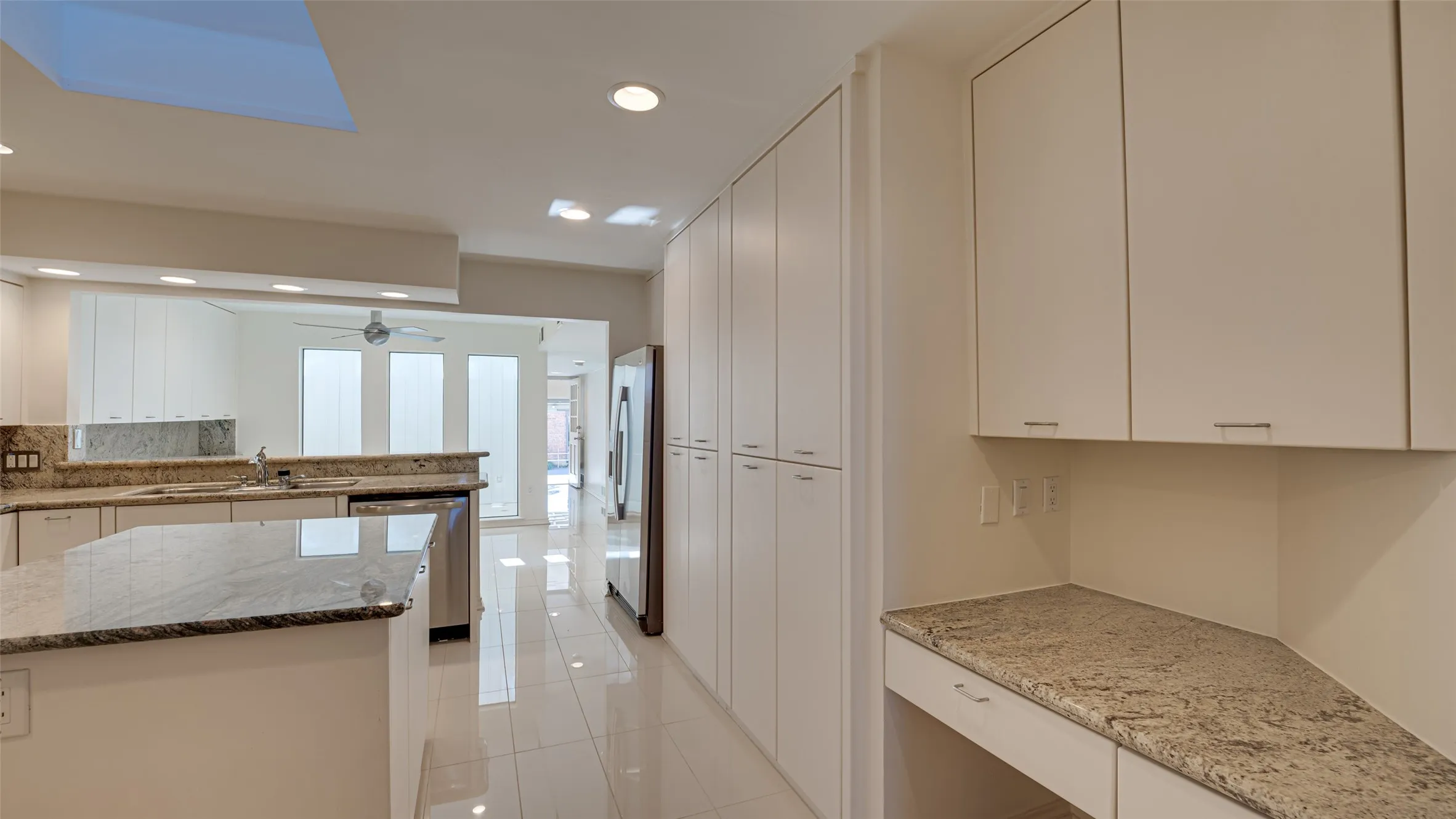 Kitchen featuring light tile patterned flooring, white cabinetry, ceiling fan, appliances with stainless steel finishes, and stone countertops