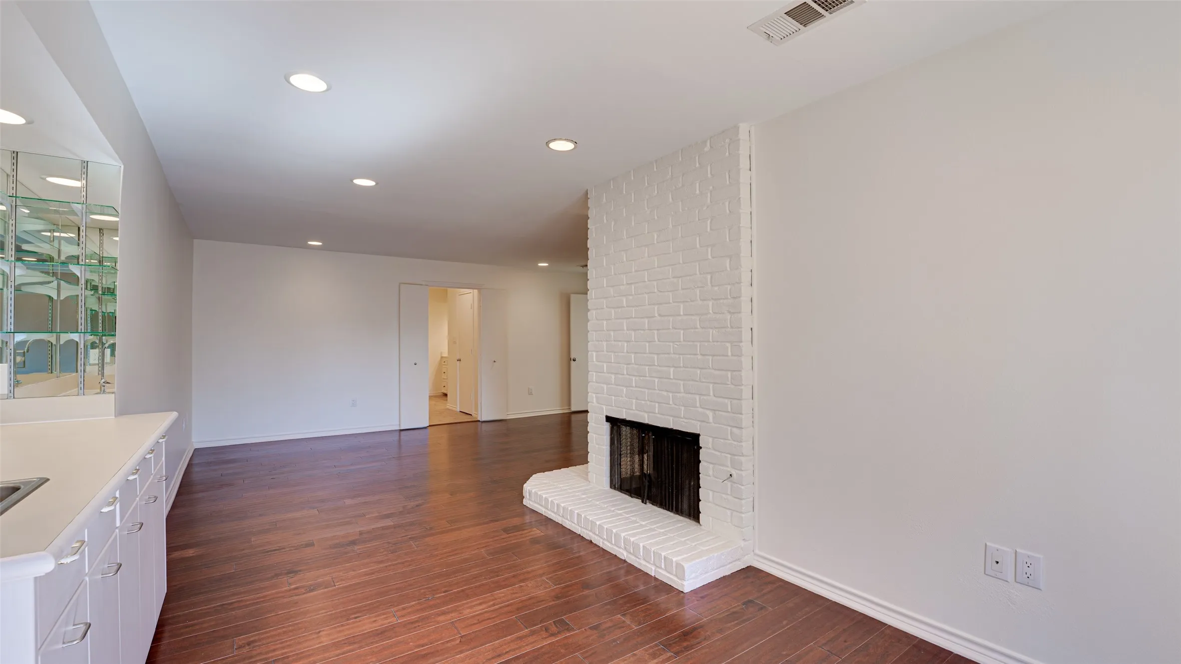 Primary bedroom featuring brick wall, a fireplace, and hardwood / wood-style floors