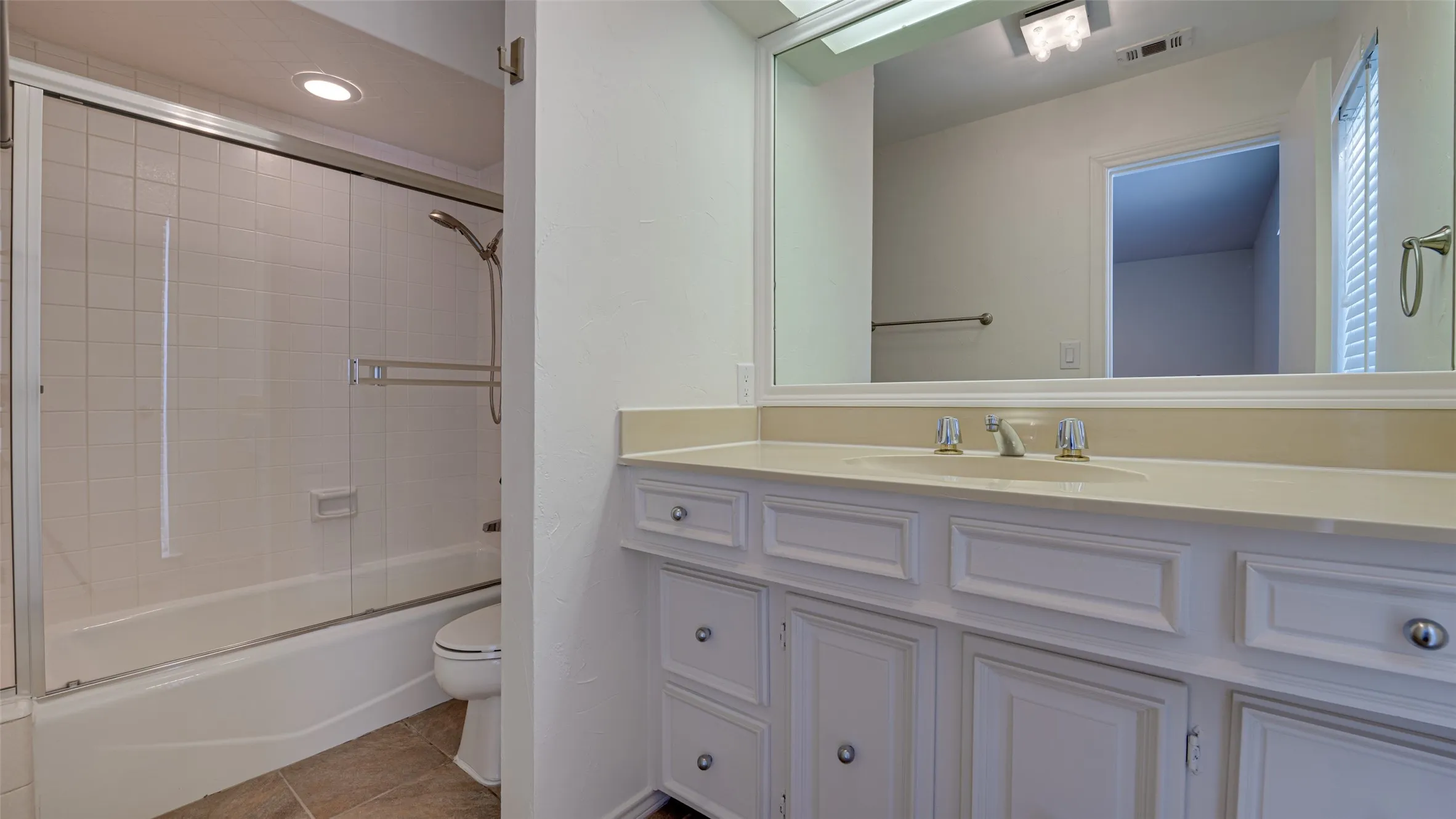 Full bathroom featuring vanity, tile patterned flooring, bath / shower combo with glass door, and toilet