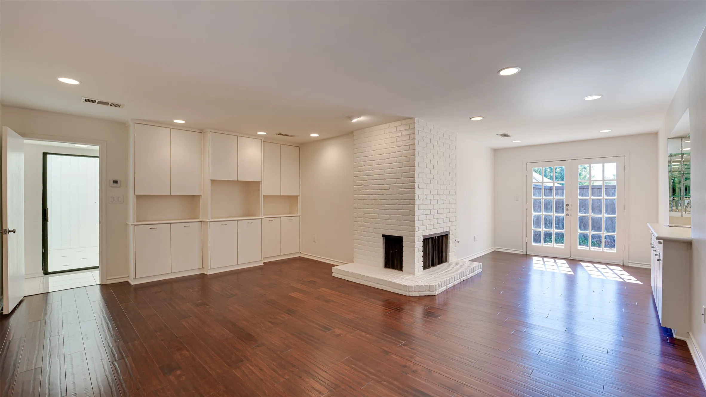 Primary bedroom featuring brick wall, a brick fireplace, and dark hardwood / wood-style floors