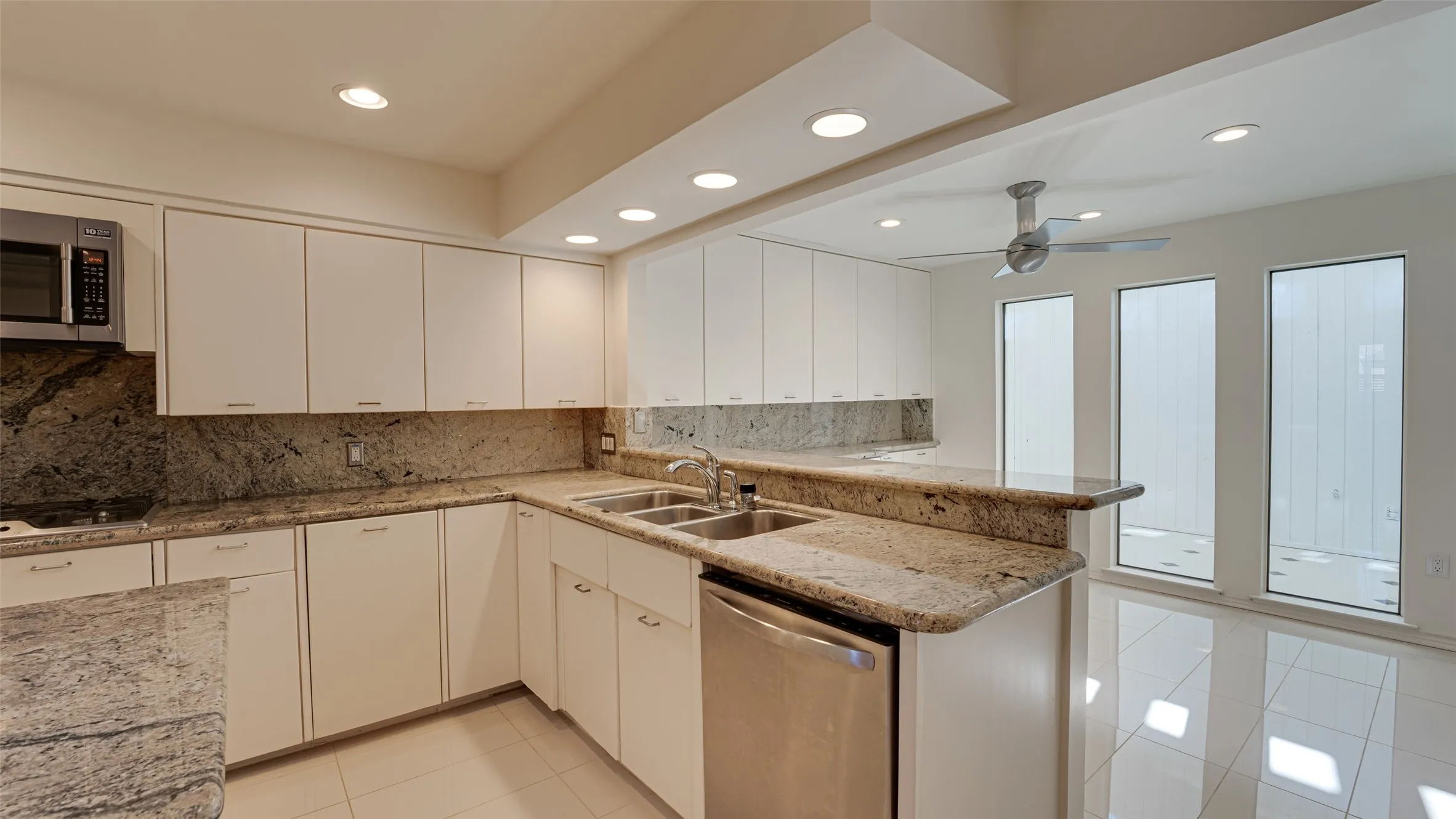 Kitchen featuring sink, kitchen peninsula, ceiling fan, and stainless steel appliances